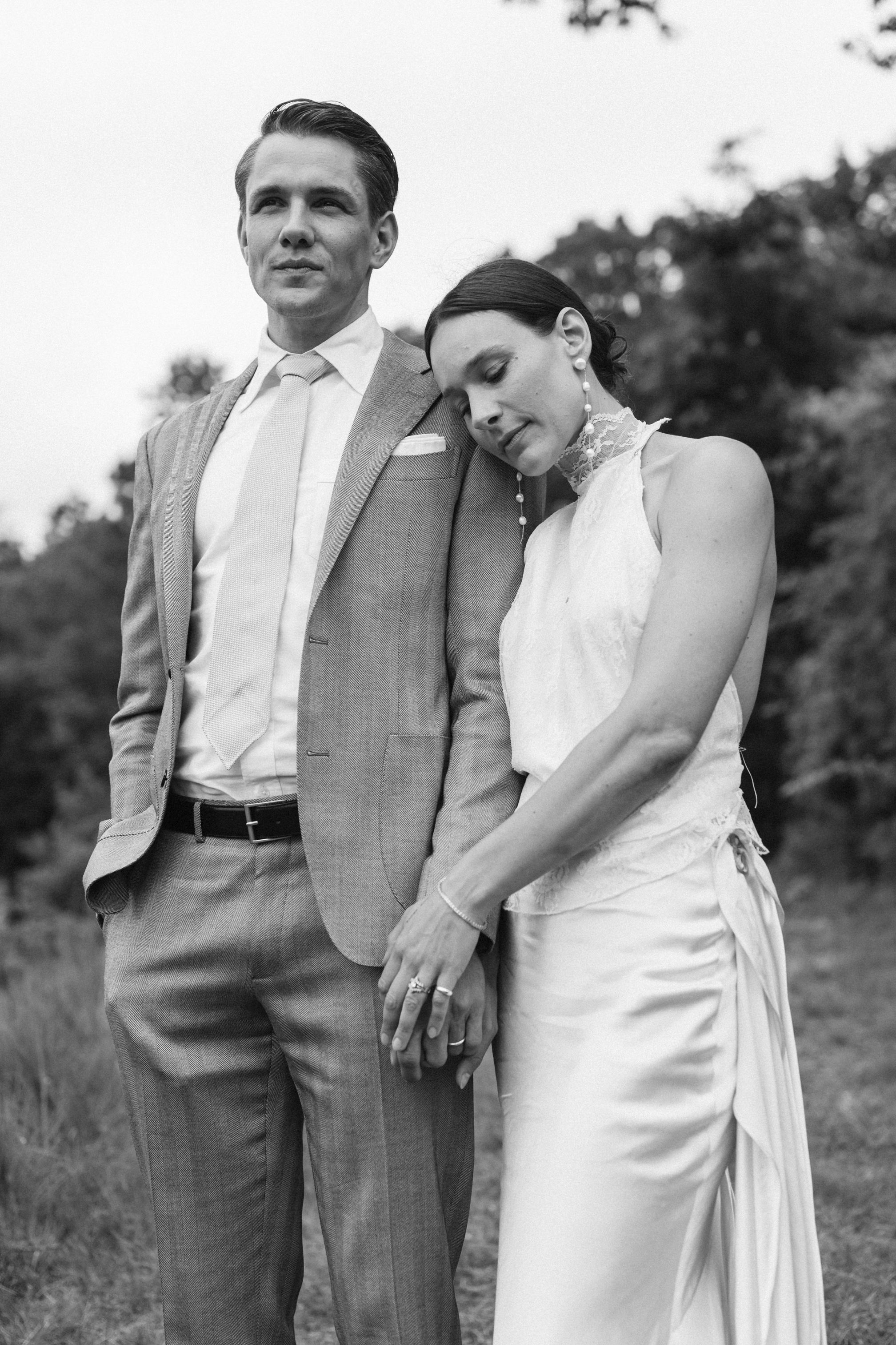 A series of romantic black and white wedding photos showing a couple embracing outdoors in formal attire.