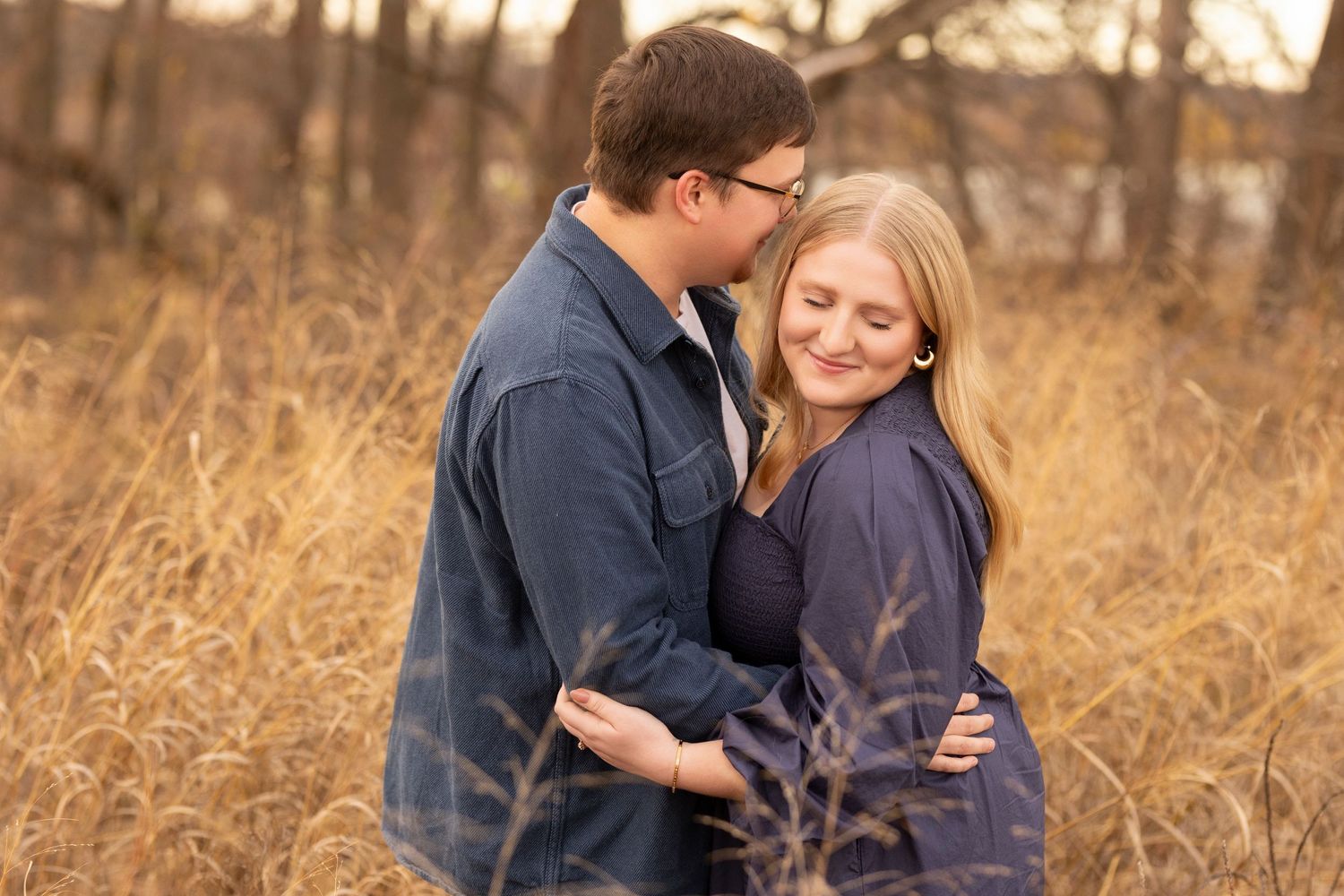 A tender embrace captured in a field of tall golden grass during sunset.