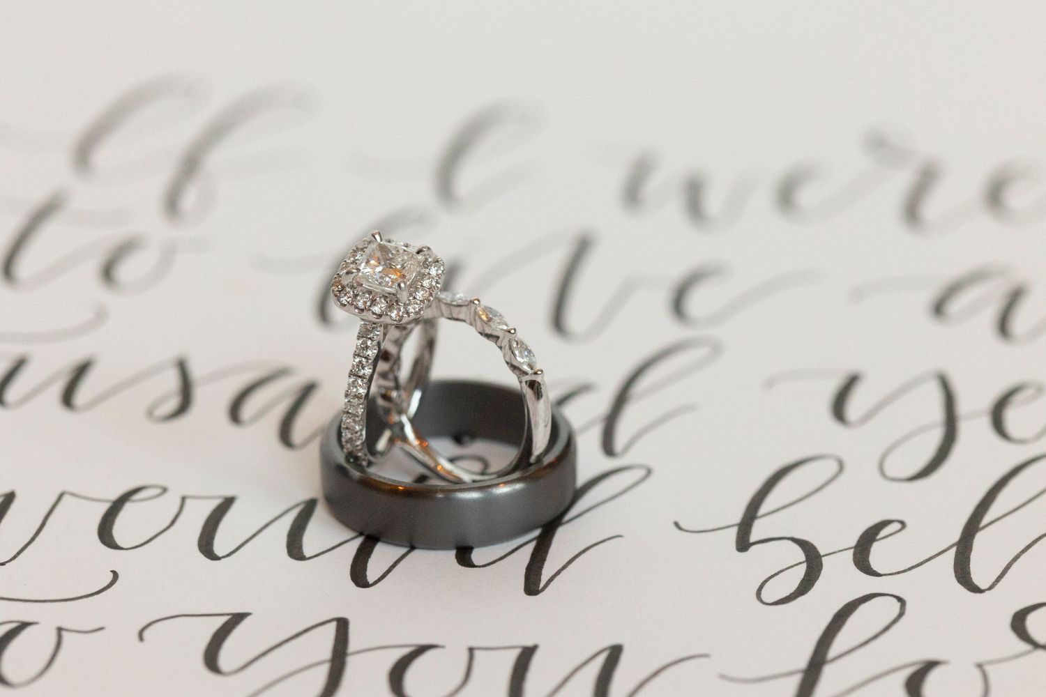 Elegant wedding rings photographed on calligraphy with artistic black and white styling.