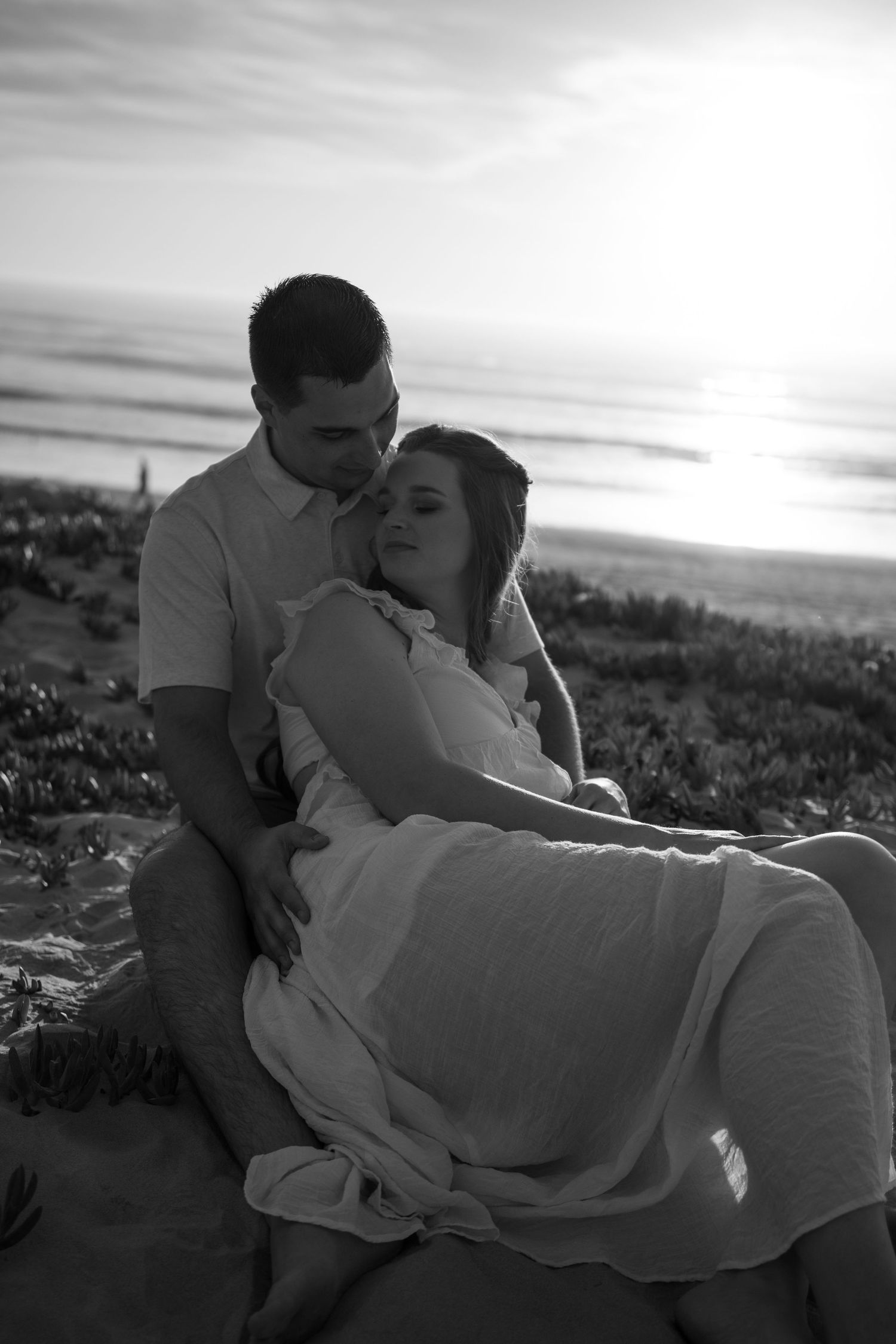 Couple embracing with their pet in golden desert landscape at sunset.