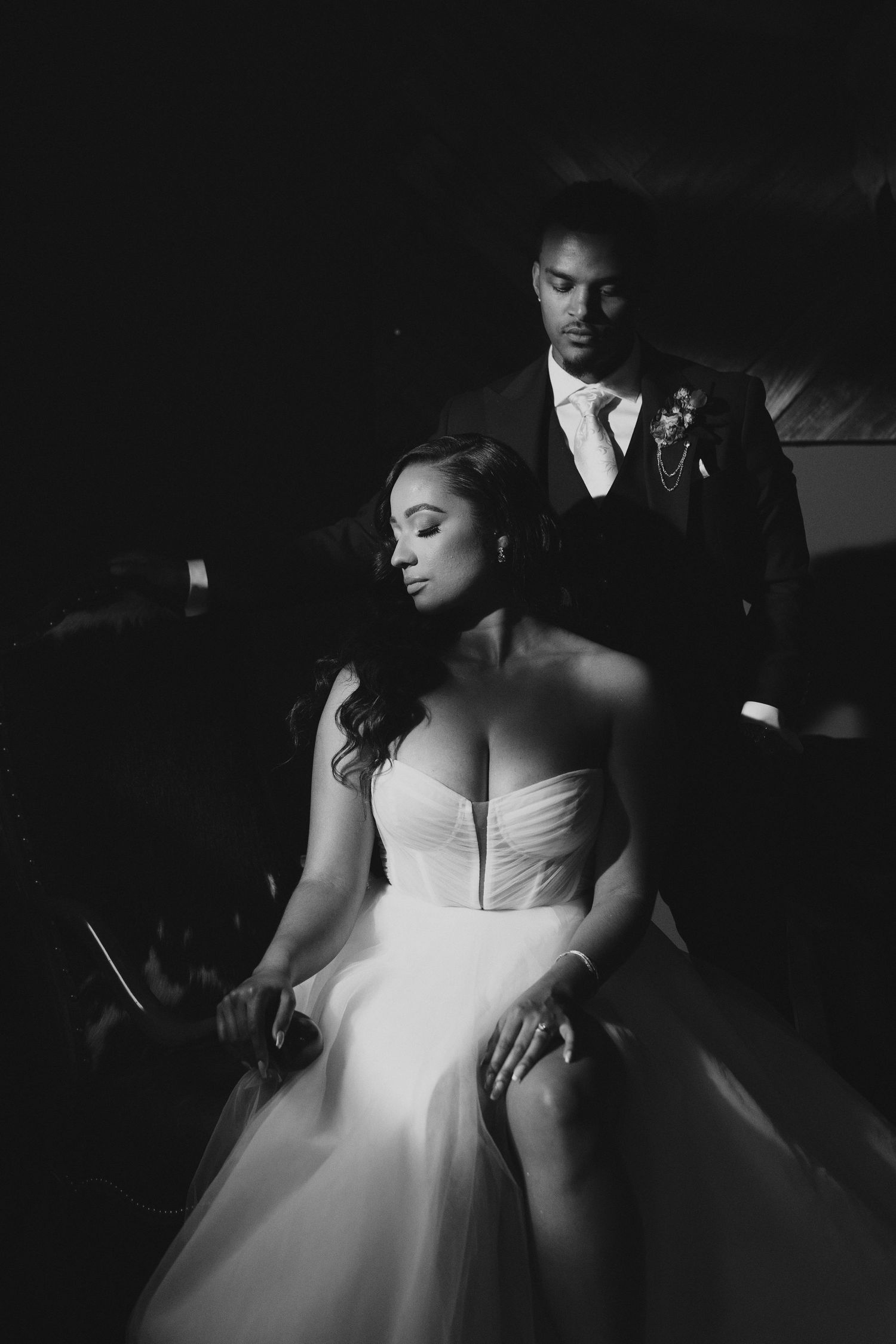 Black and white artistic long exposure photo of a couple embracing while light trails swirl around them in the darkness.