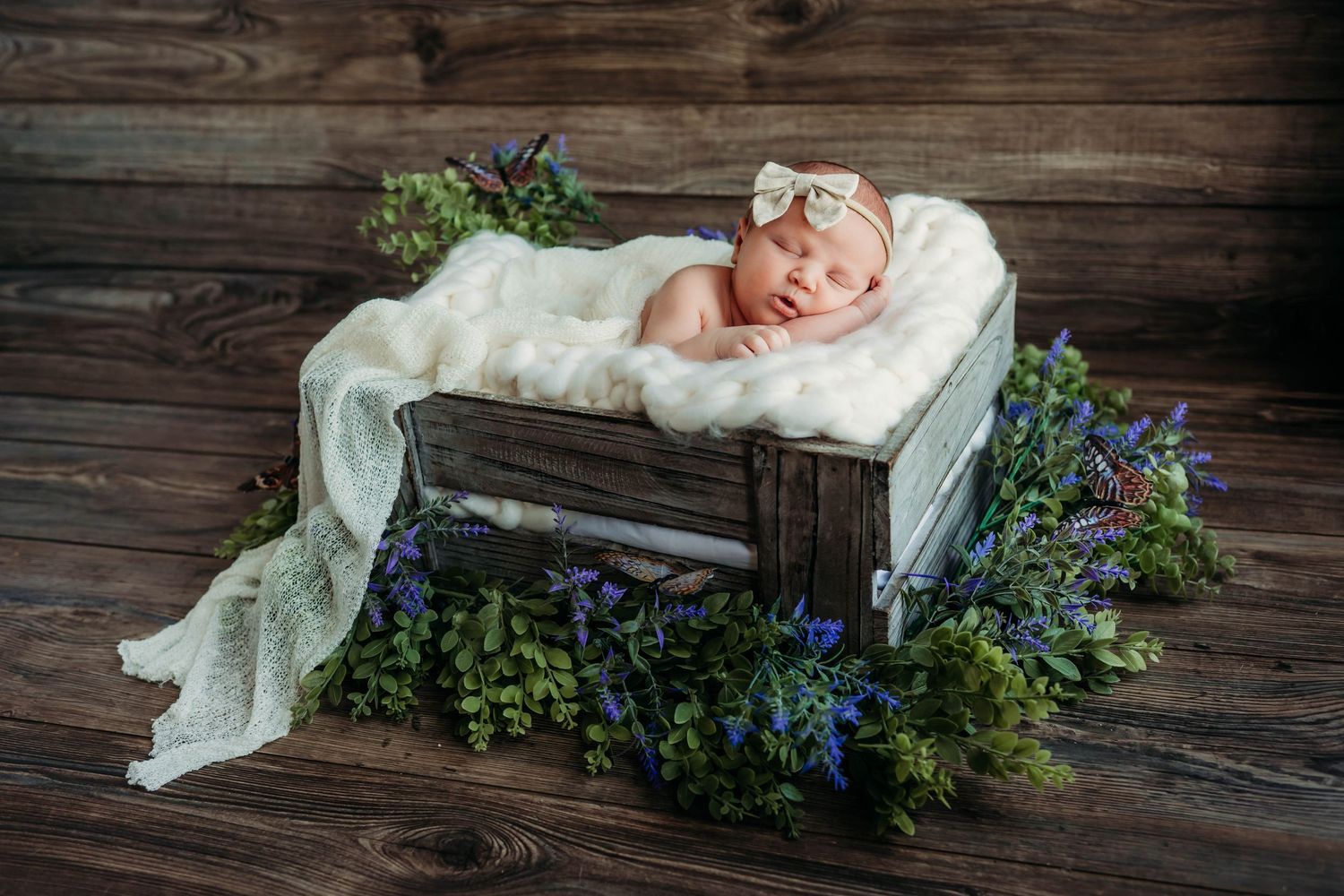 Newborn baby surrounded by colorful autumn leaves in a rustic flatlay composition with lace blanket.