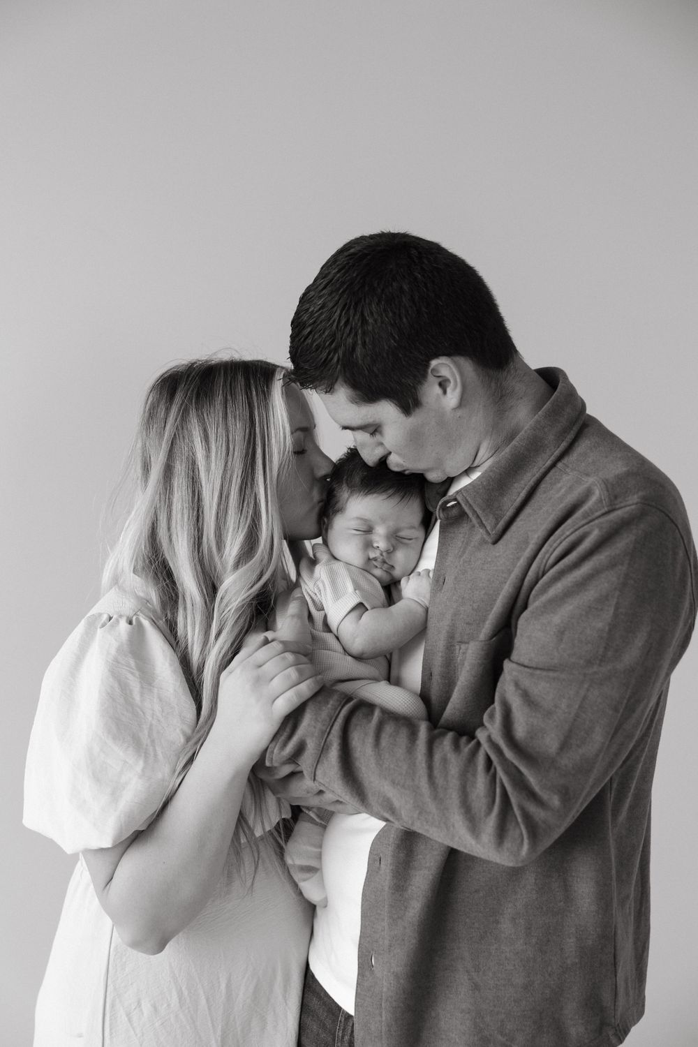 Intimate black and white portrait of parents cradling their newborn baby.
