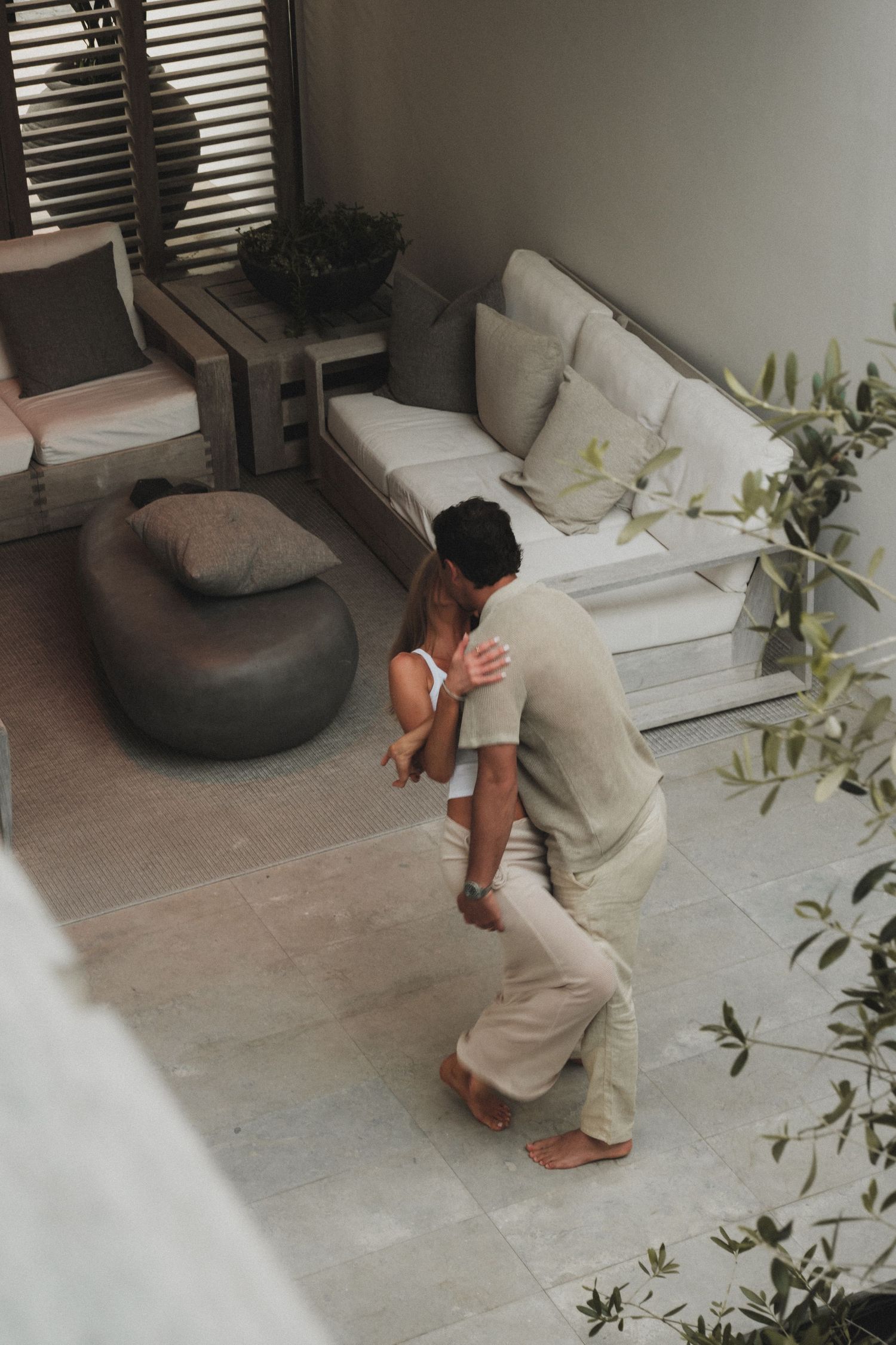 Person in casual attire bending down in a modern living room with minimalist furniture.