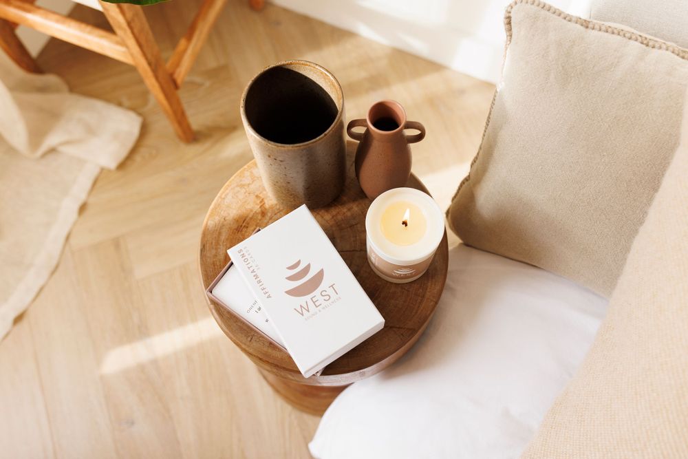 Cozy lifestyle setup with coffee, candle and ceramic items on wooden tray.