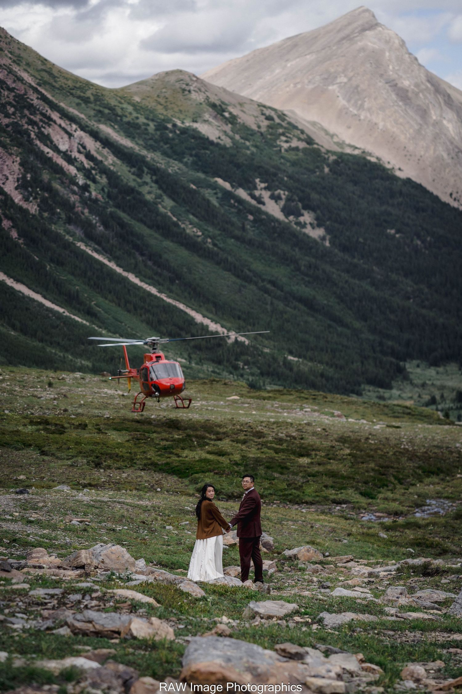 A wedding portrait against a classic Chevelle car during golden hour sunset.