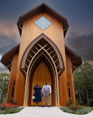 Modern wooden church with diamond window and arched entrance at sunset.