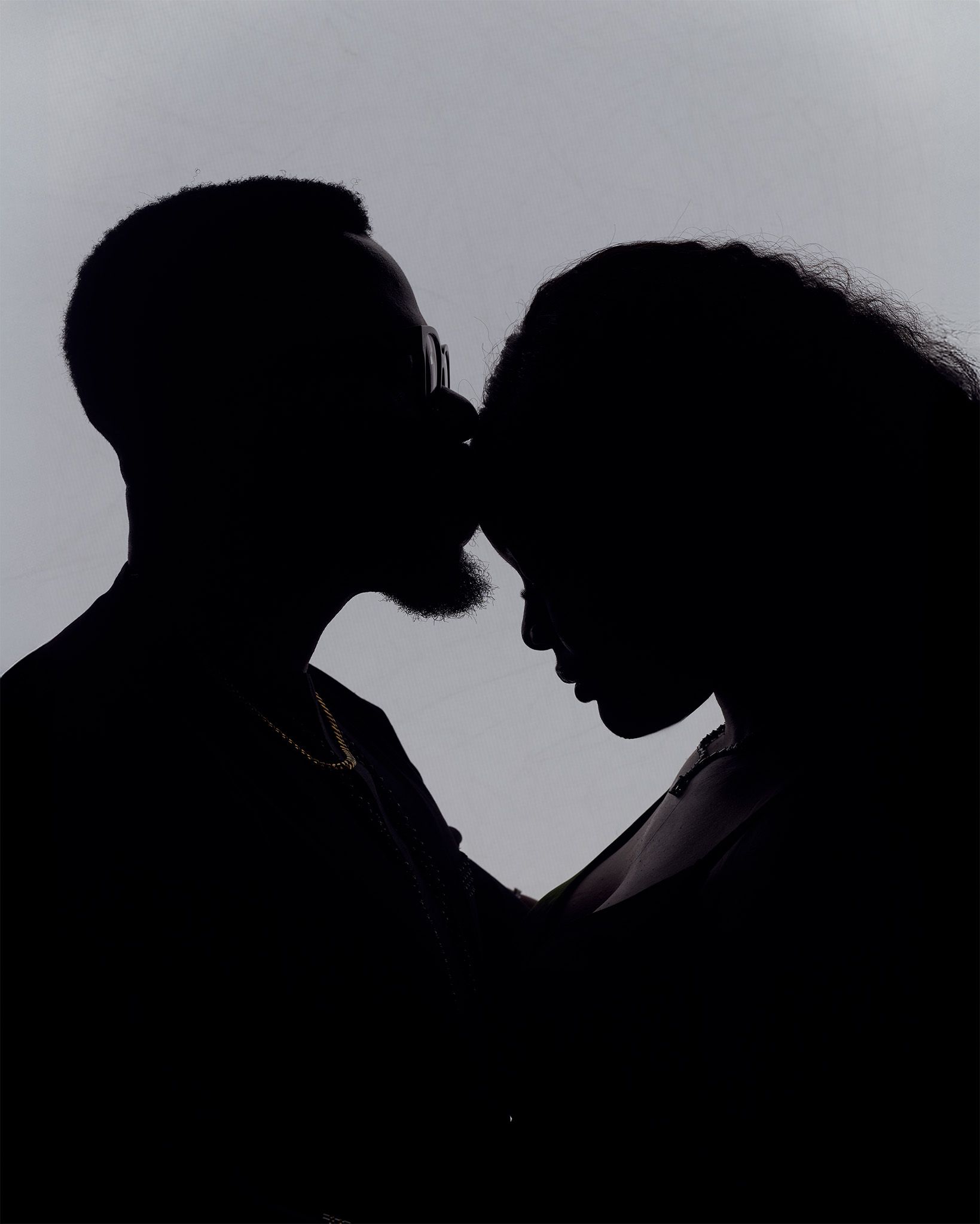 Romantic silhouette of a couple facing each other intimately against a light gray background.