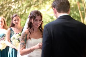 Bride reading vows during wedding ceremony with bridesmaids in teal dresses watching.