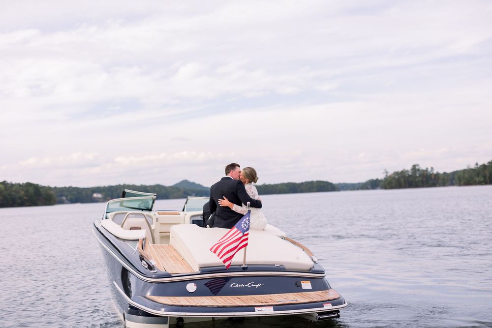 A boat speeds across a lake creating a wake on a sunny summer day with an American flag visible on the stern.