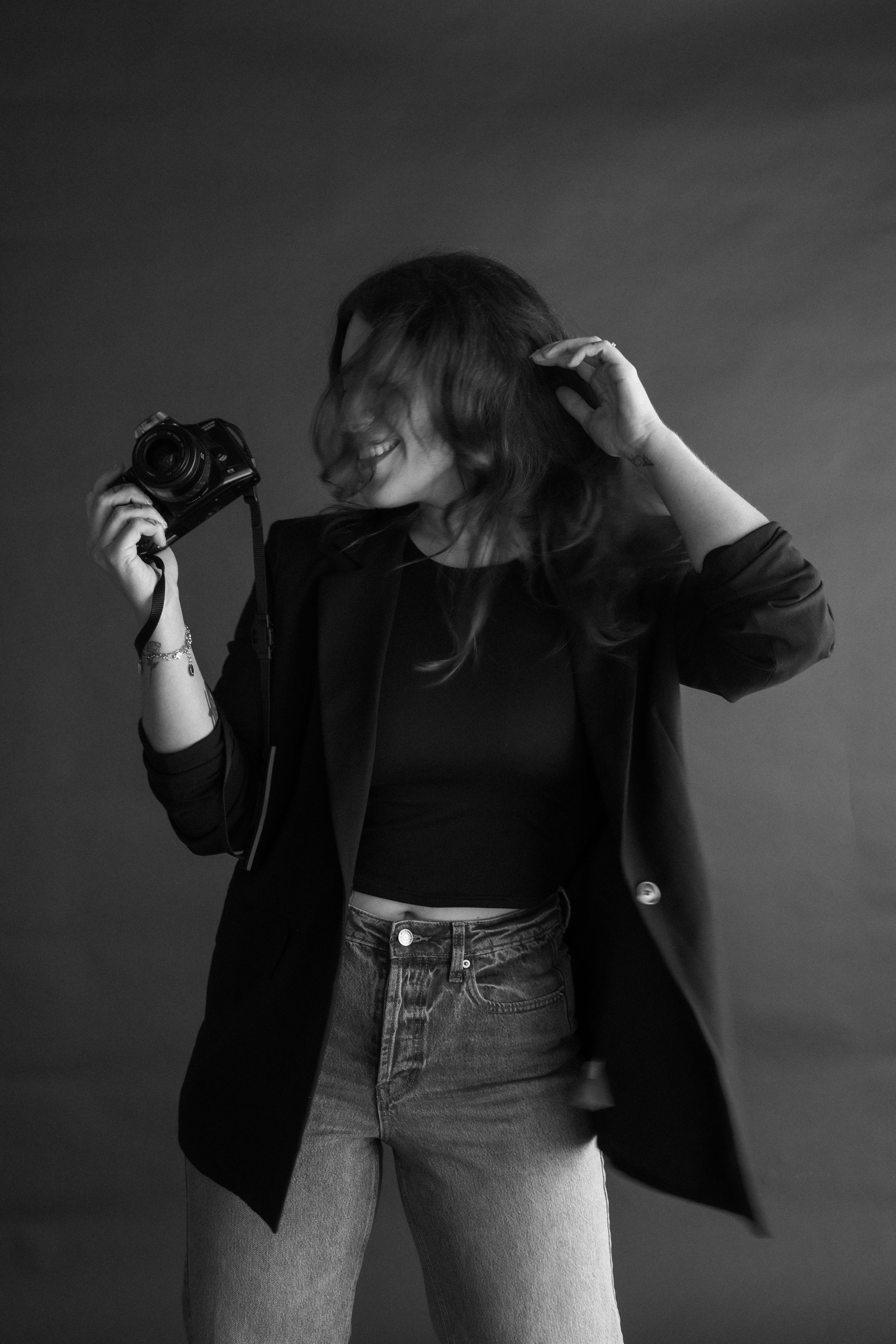 Artistic black and white photo sequence showing person in jeans and black top against gray background doing dance movements.