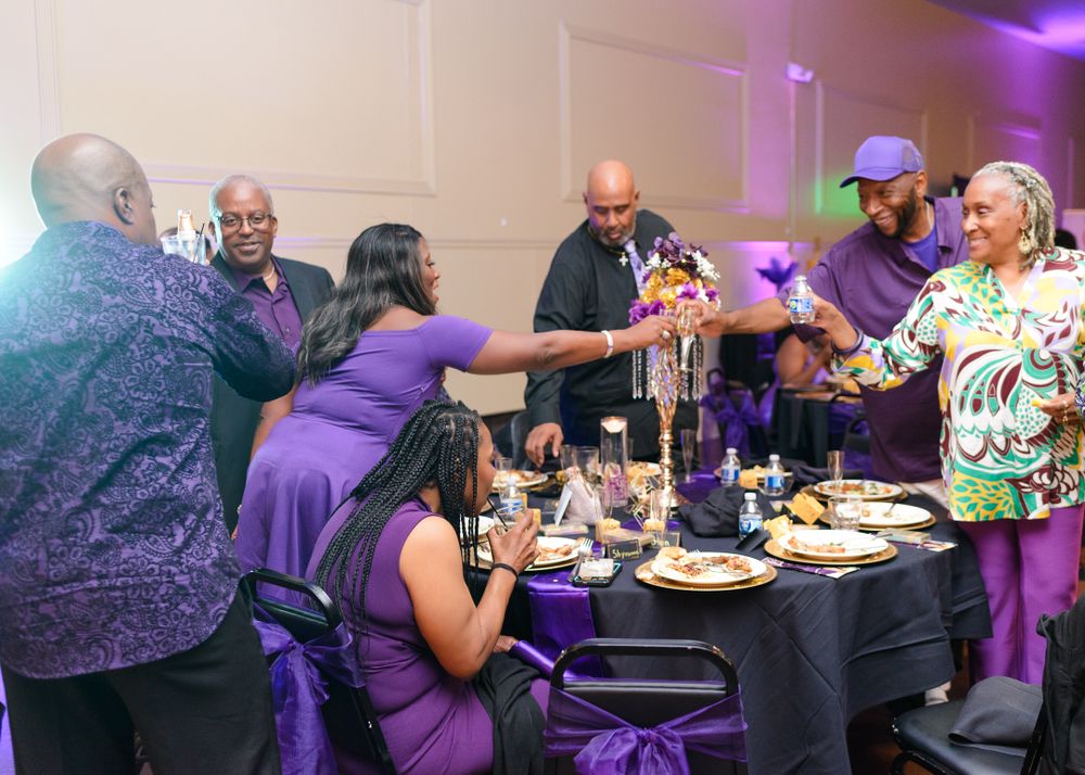 Guests enjoying dinner at round tables in a purple-lit event space.
