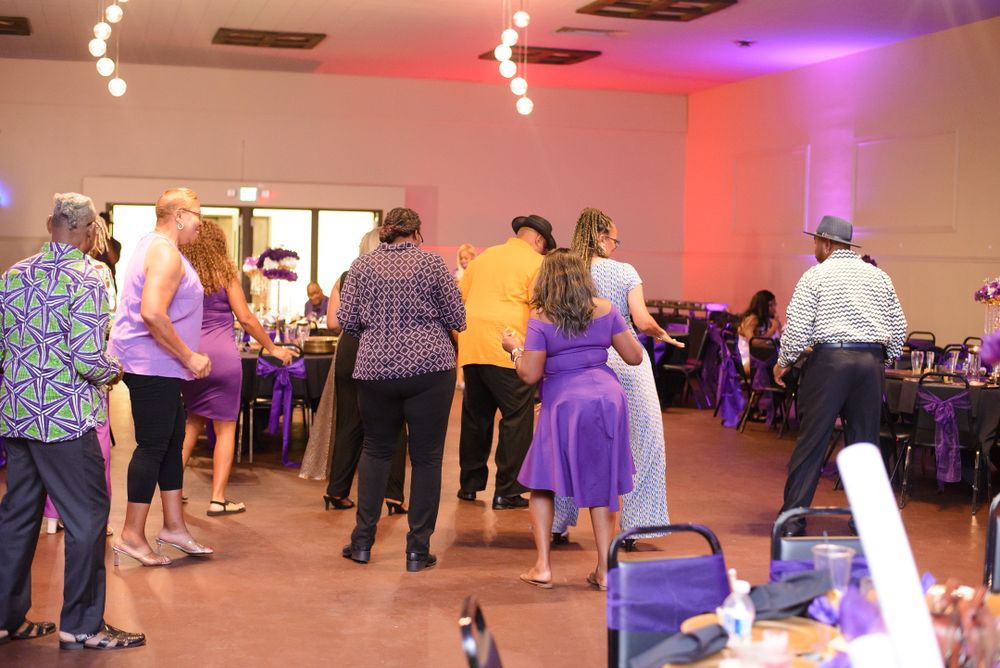 Event space with purple and red mood lighting and people dancing.