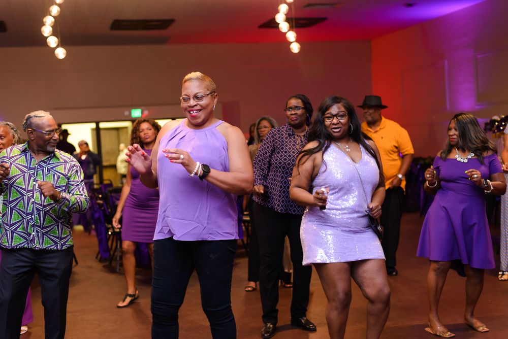 Guests dancing in a spacious venue with colorful atmospheric lighting.