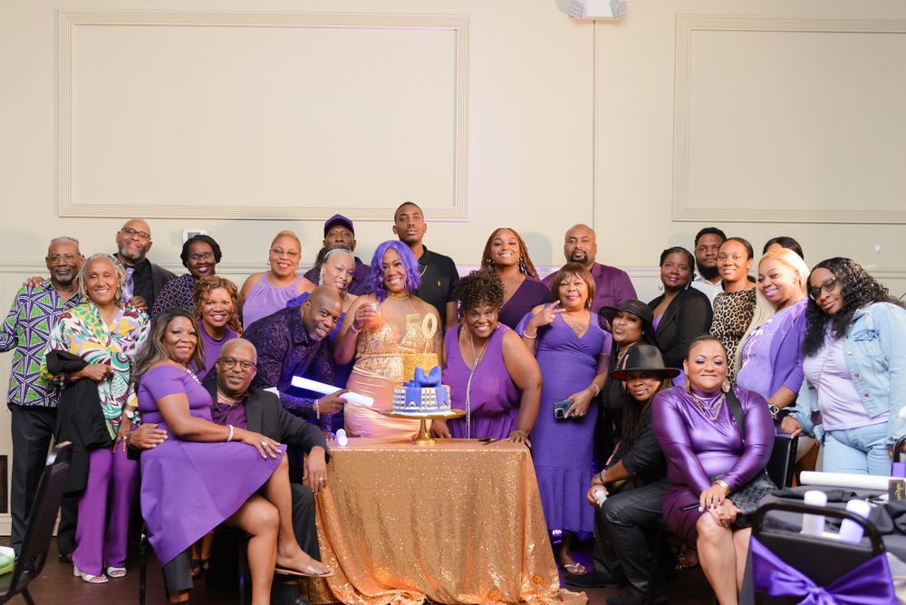 Large group photo of attendees wearing purple attire at a formal celebration.