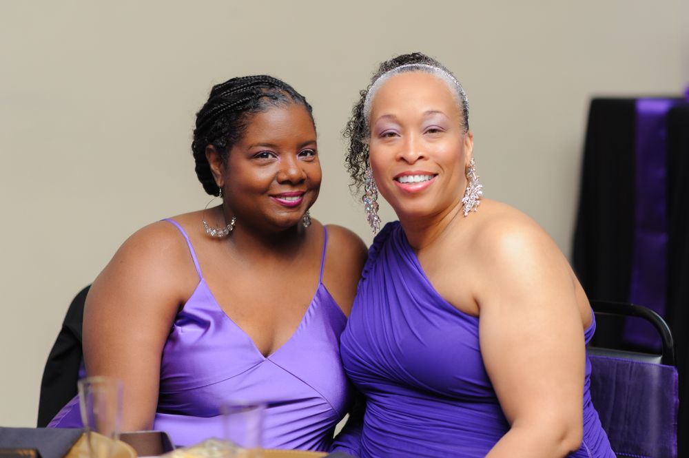 Wedding party members posing together wearing coordinated purple dresses for a formal photo.