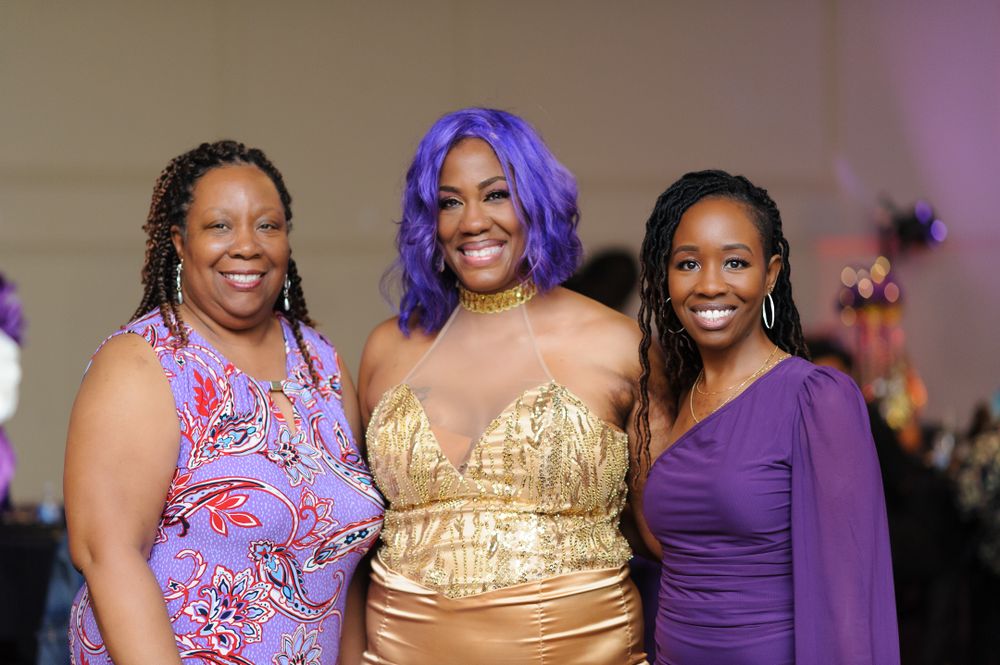 Group photo of wedding attendees wearing colorful dresses including gold and purple.