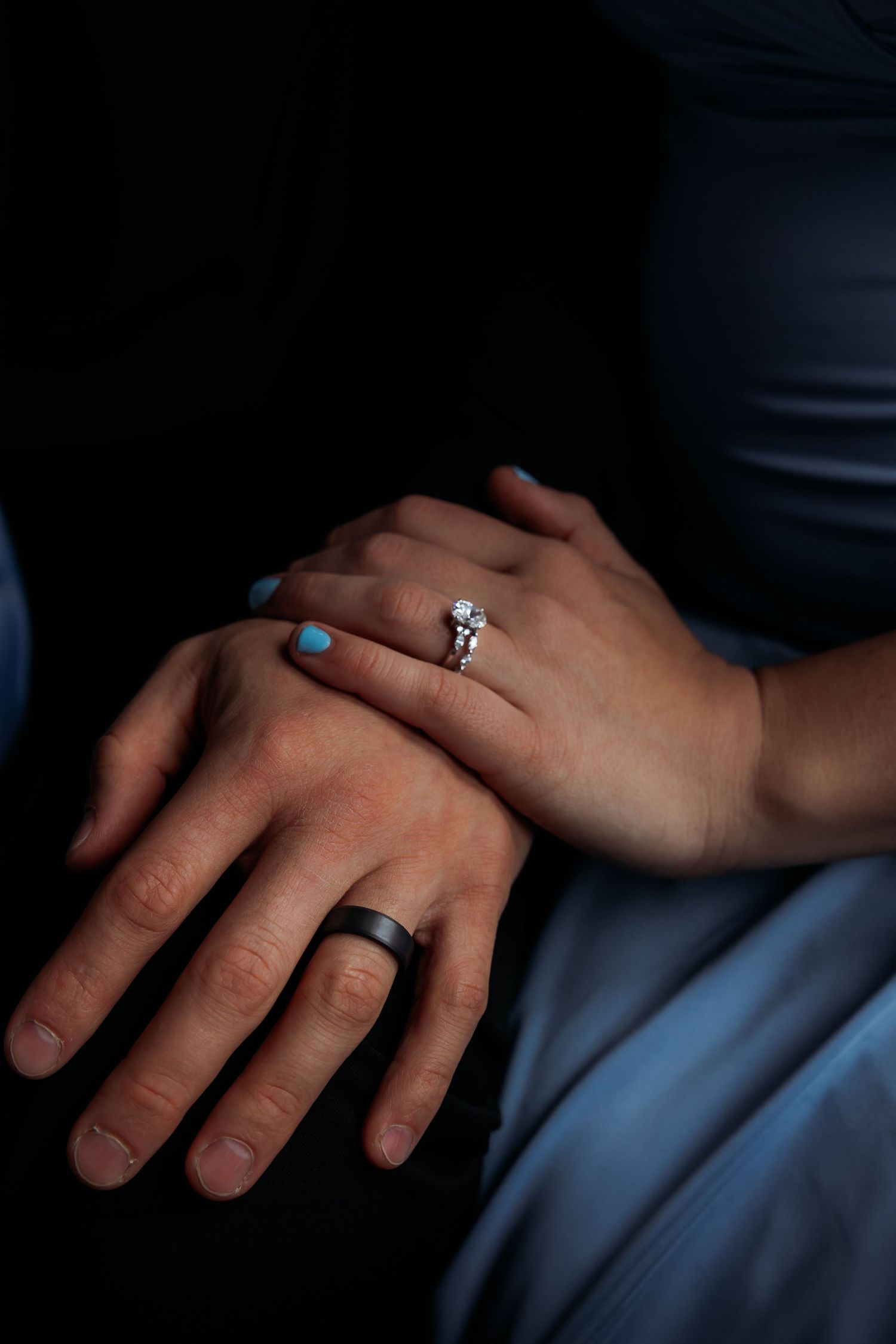 Diamond engagement ring displayed with blush pink roses and white manicured nails.