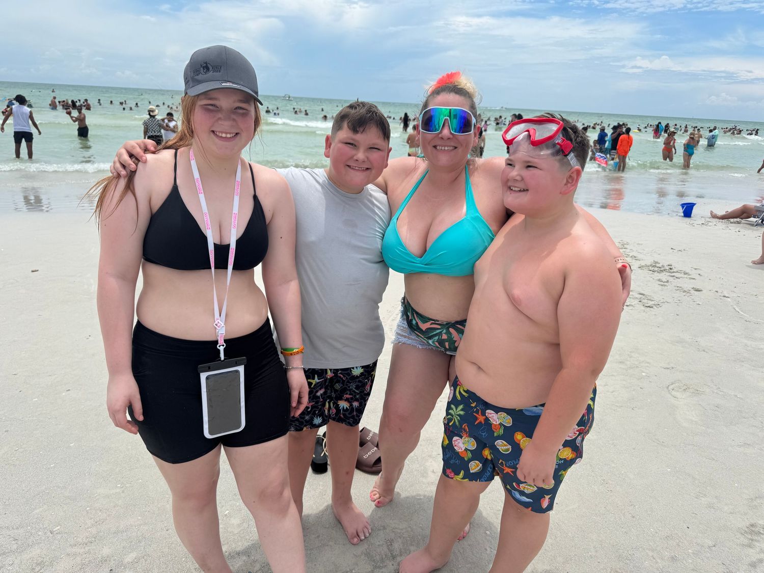 Group enjoying a sunny day at the beach with ocean waves in background.