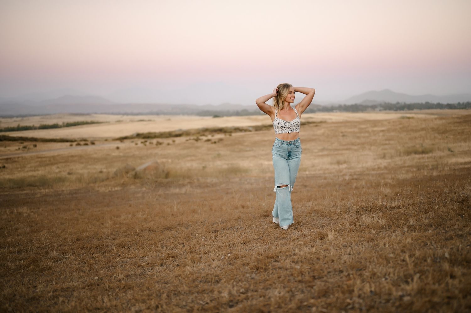Santa Barbara high school senior photoshoot by Ventura senior portrait photographer of girl standing in field at sunset
