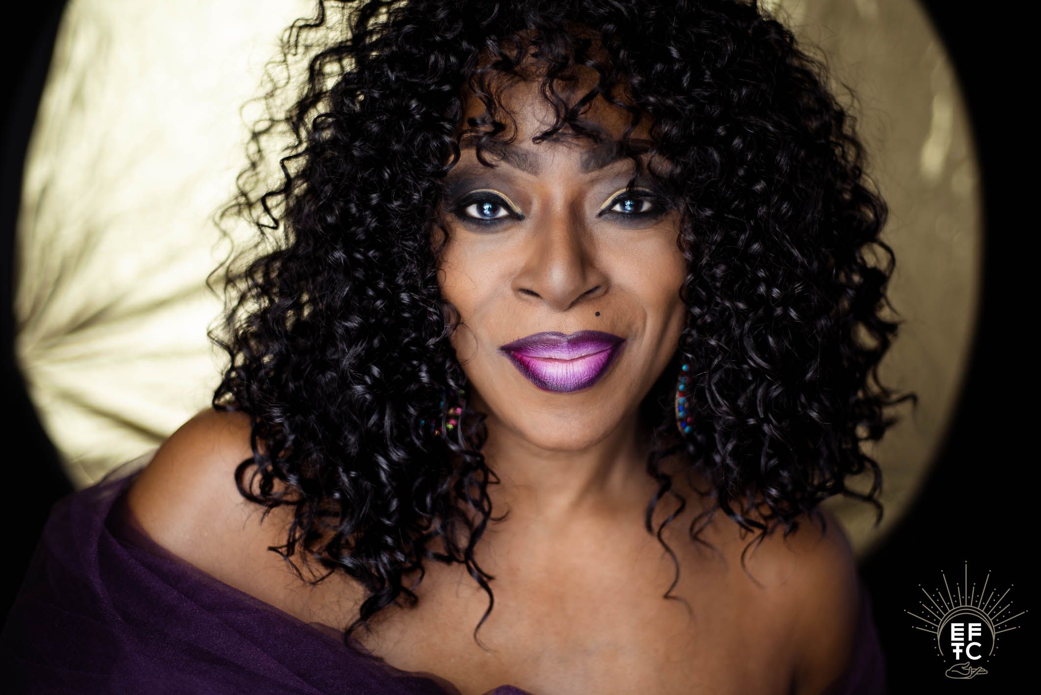 Person with curly black hair and purple lipstick poses in a collage of similar glamorous headshots.