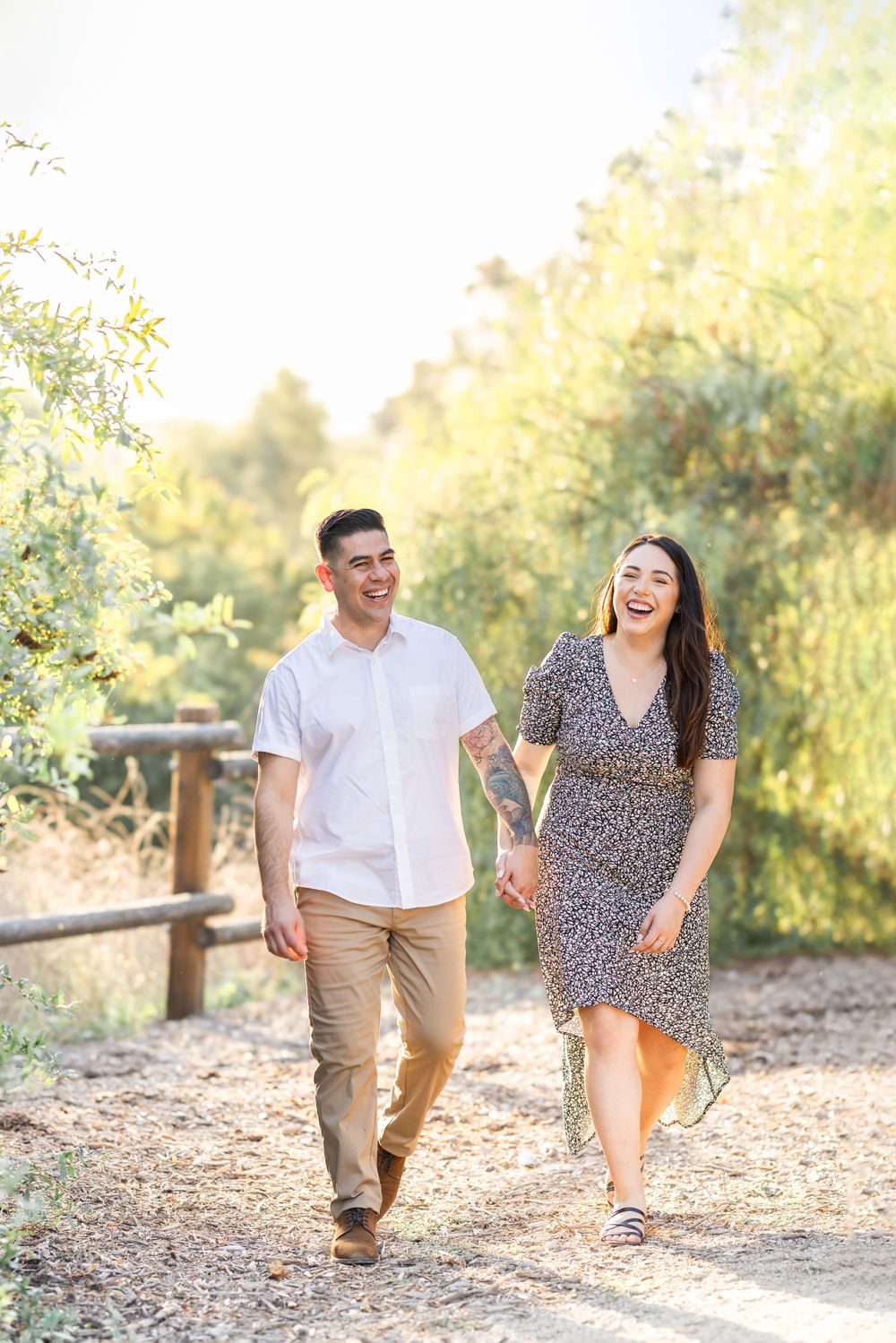 Couple walking and laughing together on nature trail during golden hour.
