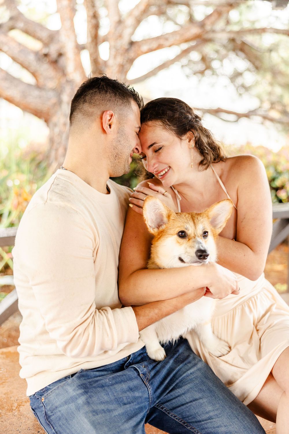 Couple sharing intimate moment with their Corgi dog during outdoor photoshoot.