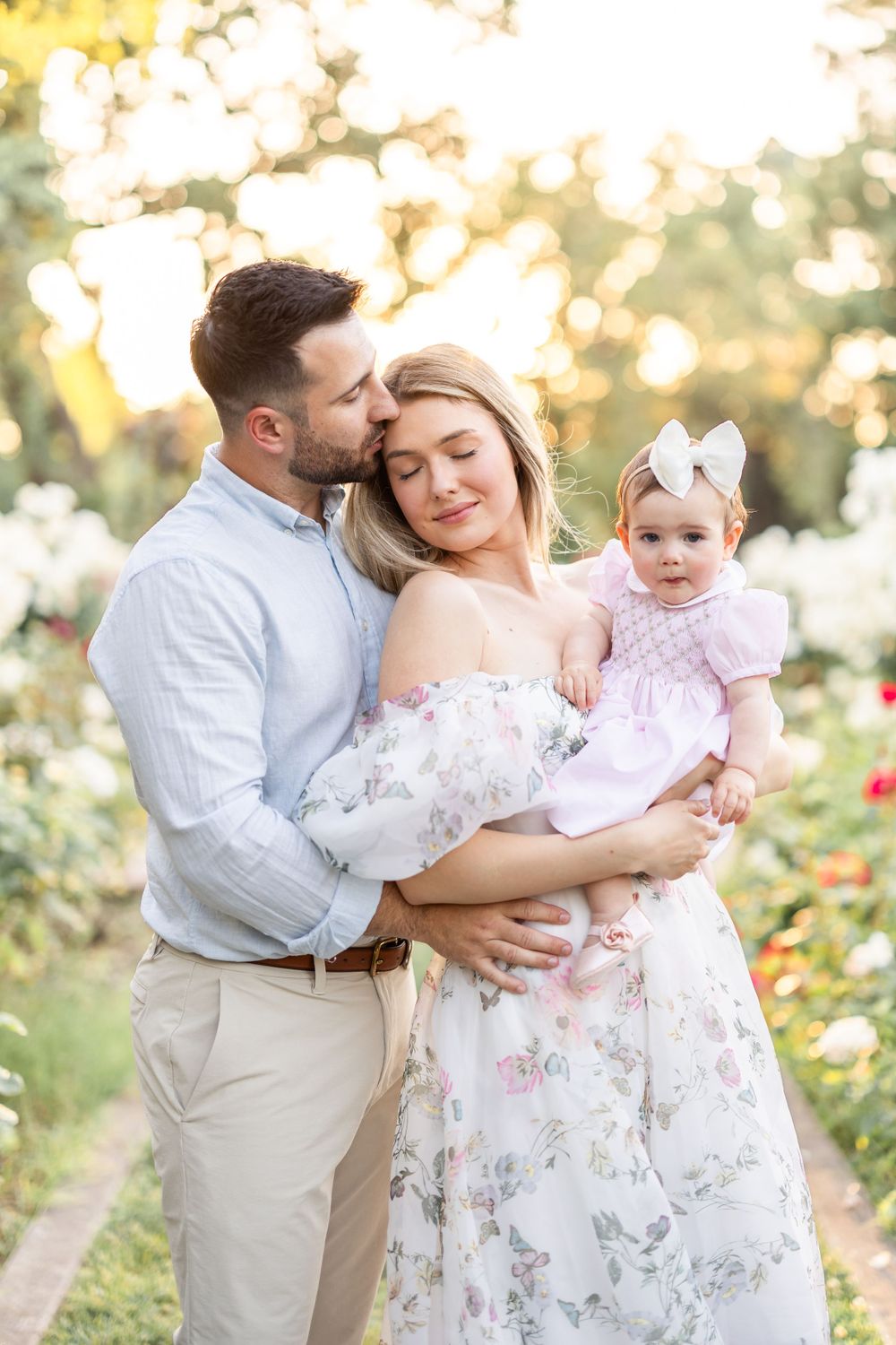 Family shares tender moments together in a sunlit garden setting.