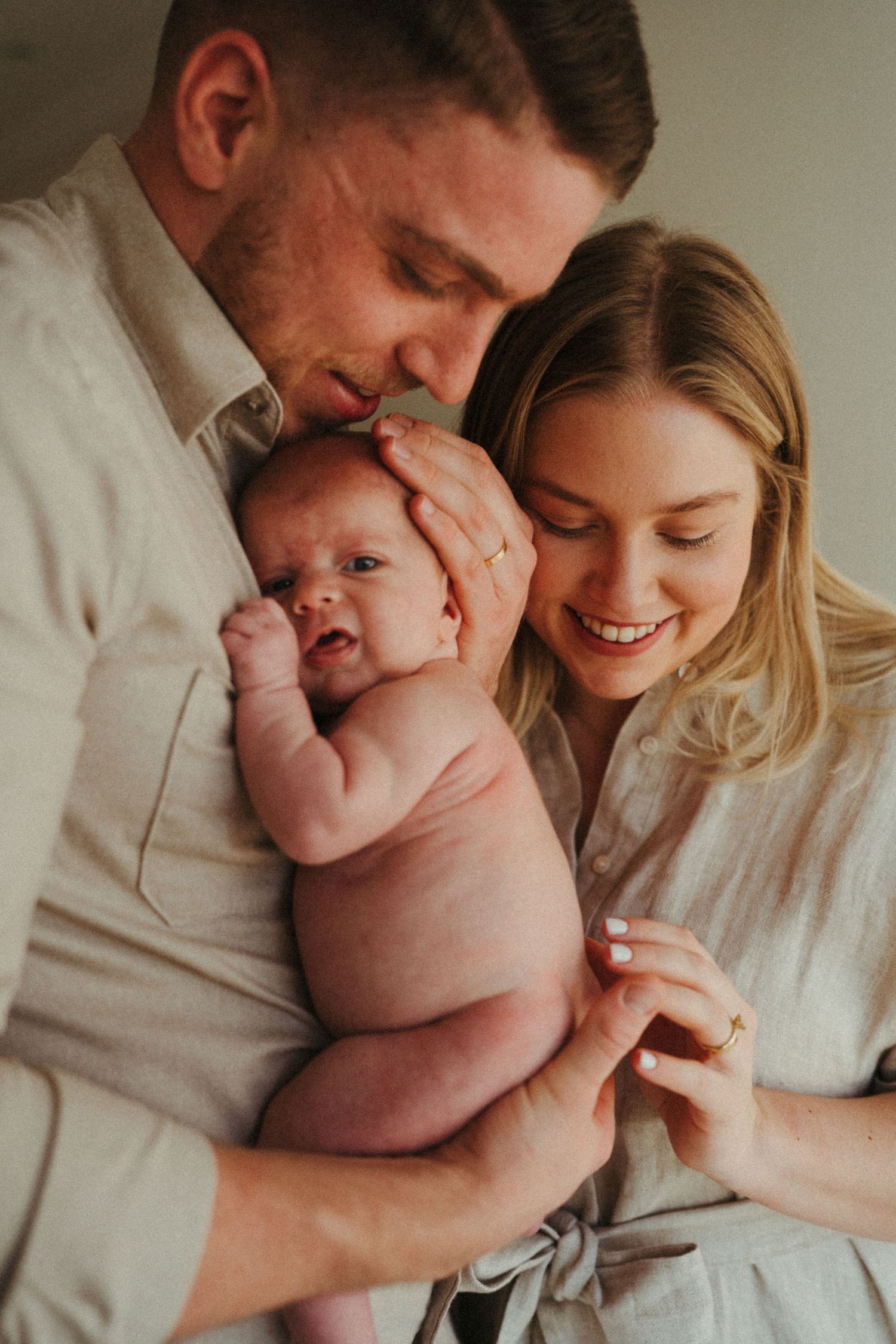 Tender family moments with newborn baby in soft natural lighting.