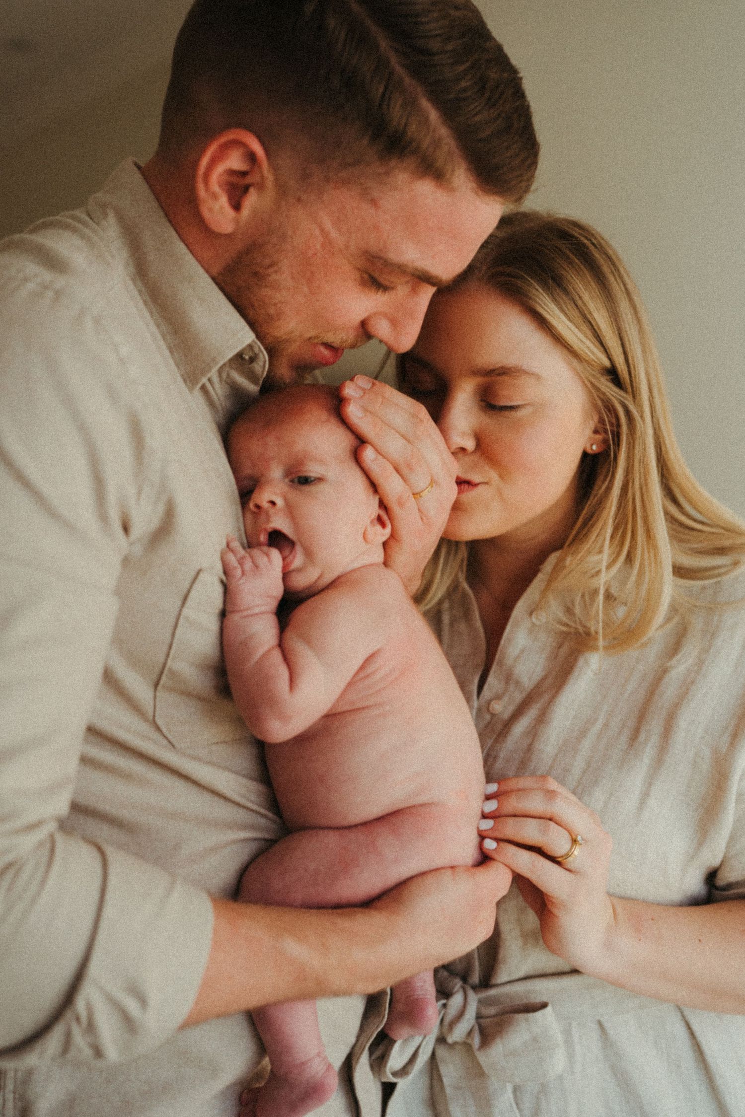 Intimate family portrait series showing gentle moments with a newborn.