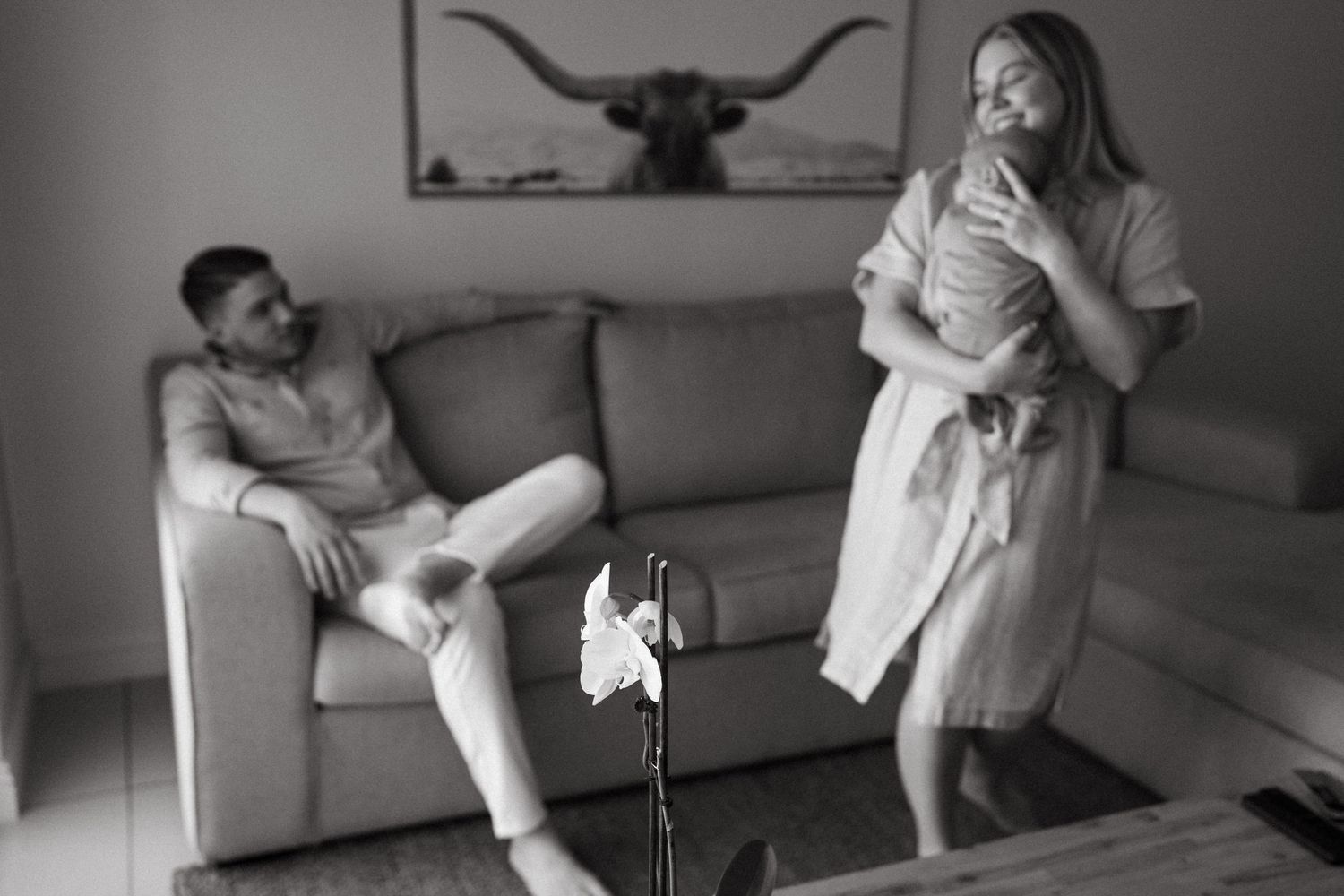 A tender family moment captured in black and white showing affectionate interactions in a living room setting.