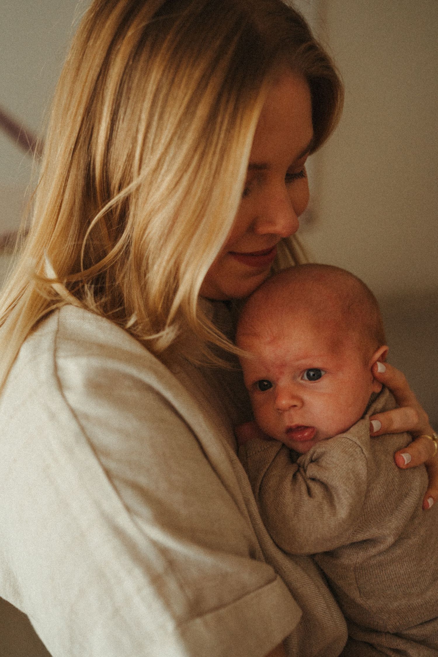 Gentle close-up moments between parent and infant in soft, natural lighting.