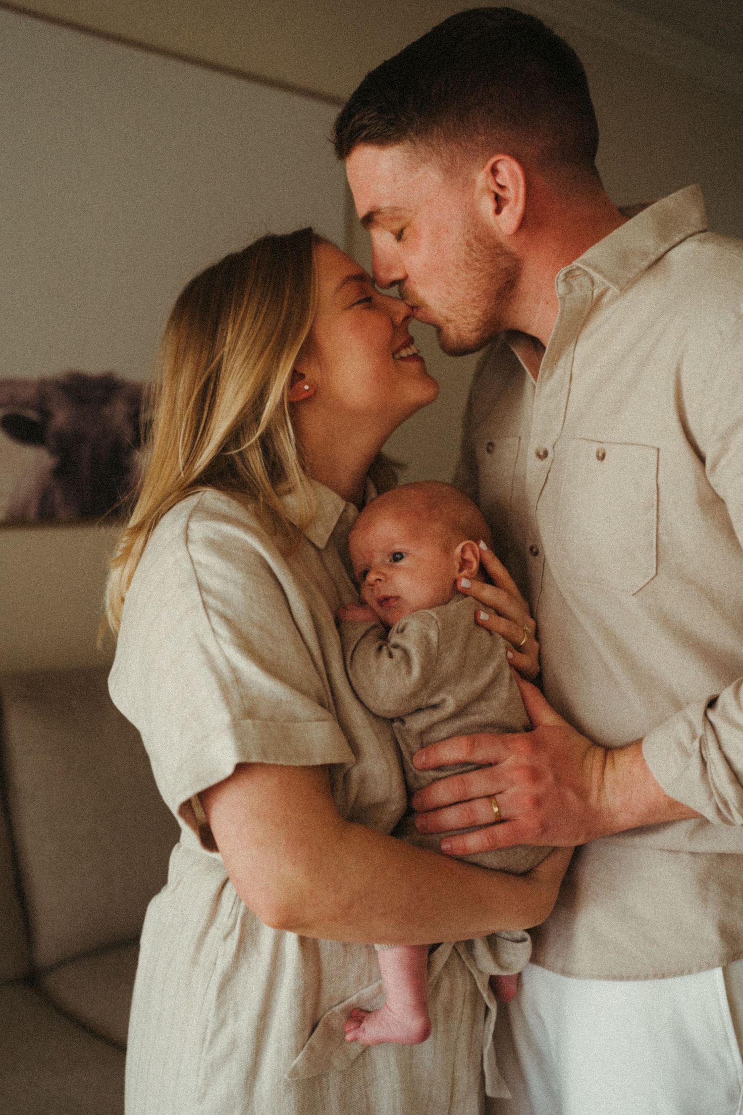 Sweet family interaction captured in warm tones showing tender moments with an infant.