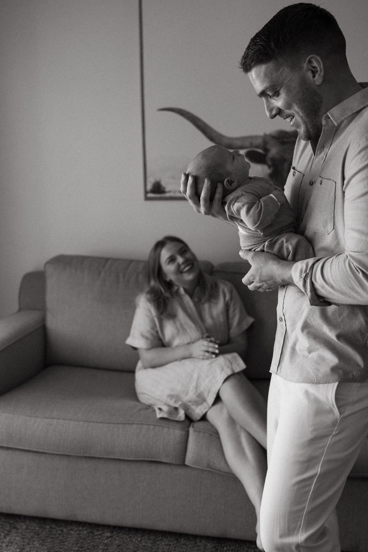 Black and white series showing playful family moments on a comfortable living room couch.
