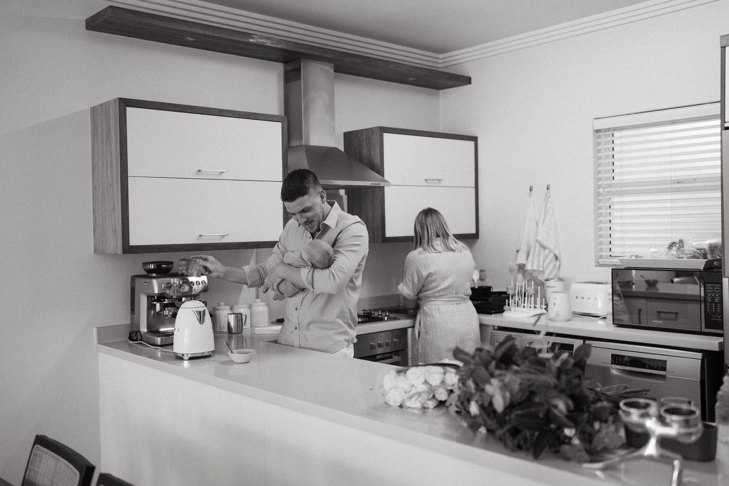 Modern kitchen interior with white cabinets and stainless steel appliances shown in black and white.