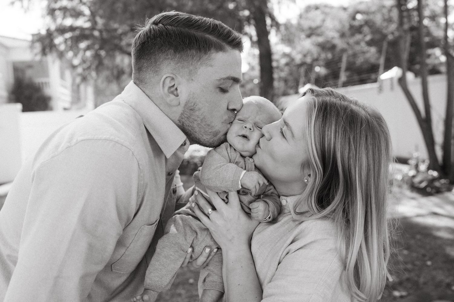 A sweet family photoshoot outdoors with neutral toned clothing and natural lighting.