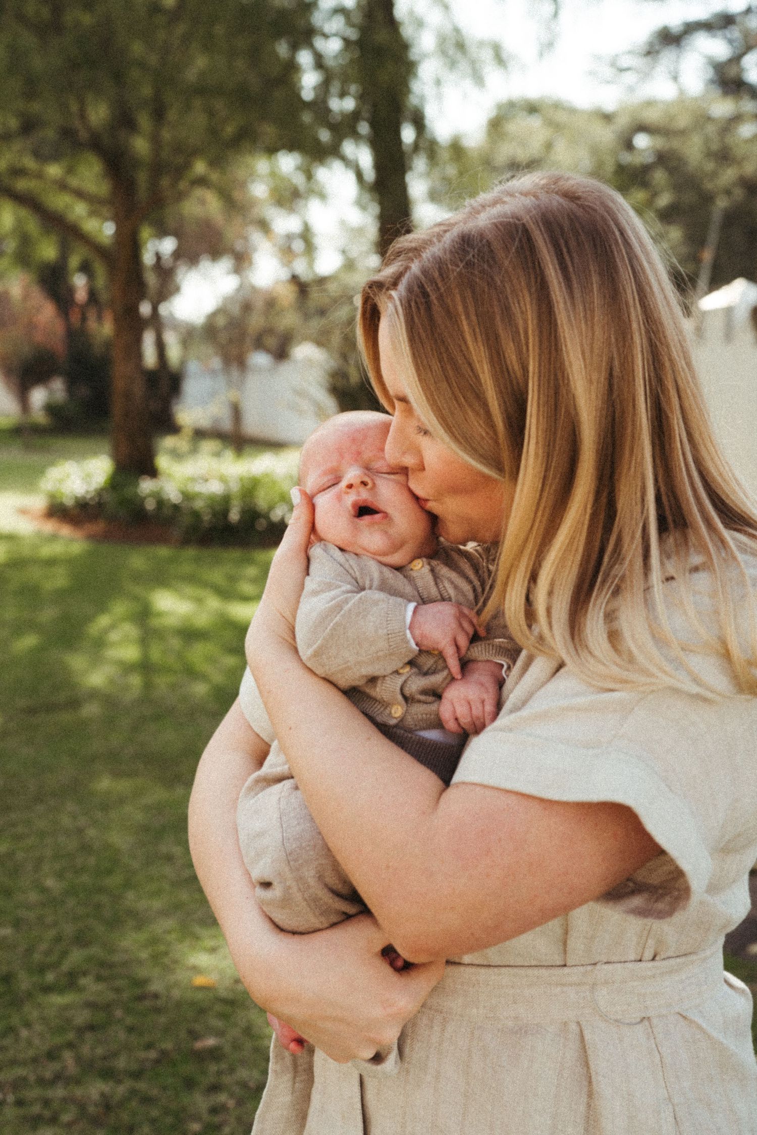 Loving family embraces in a backyard setting wearing coordinated beige outfits.