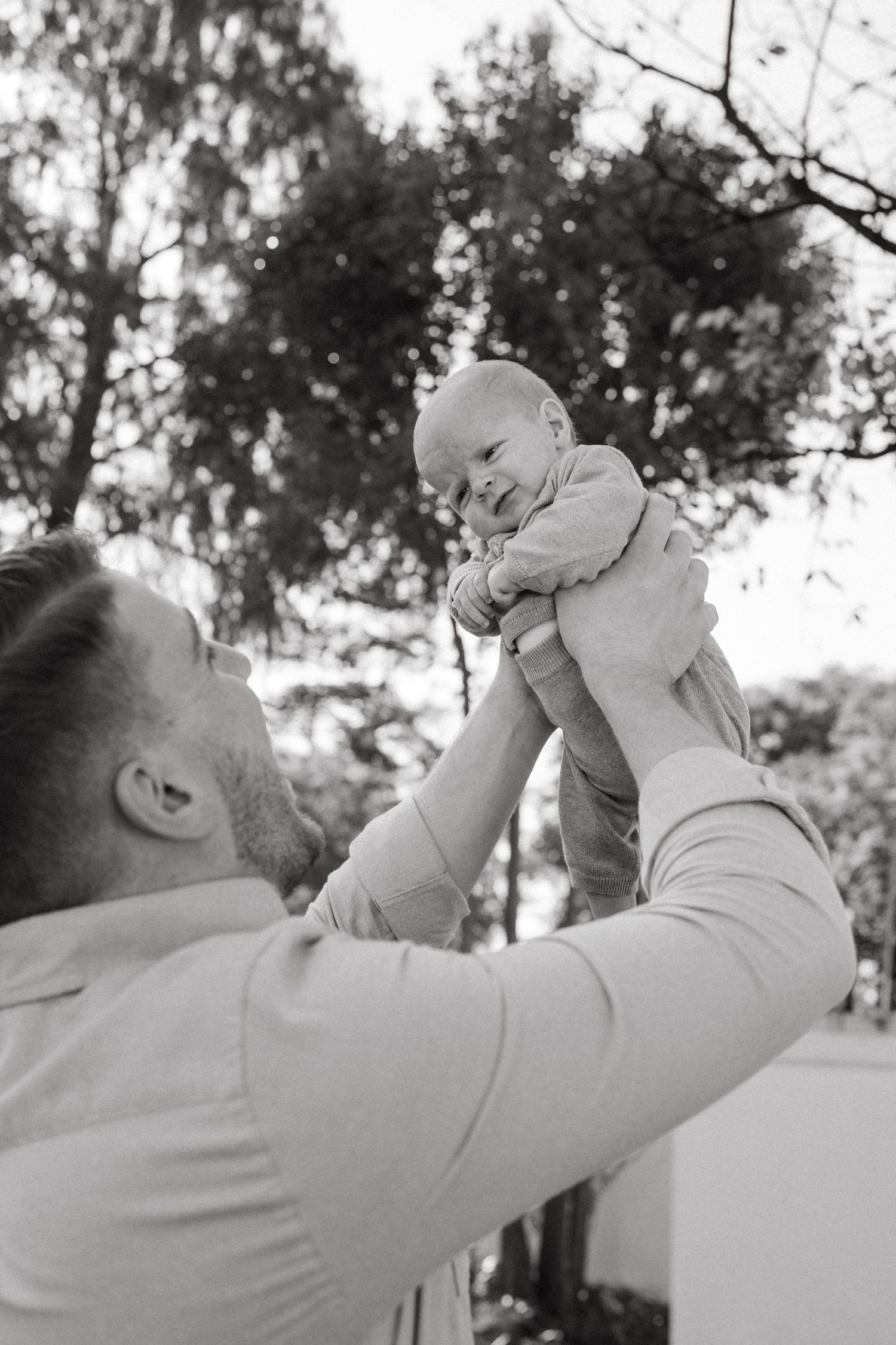 Black and white series of a parent lifting infant skyward in playful moment.