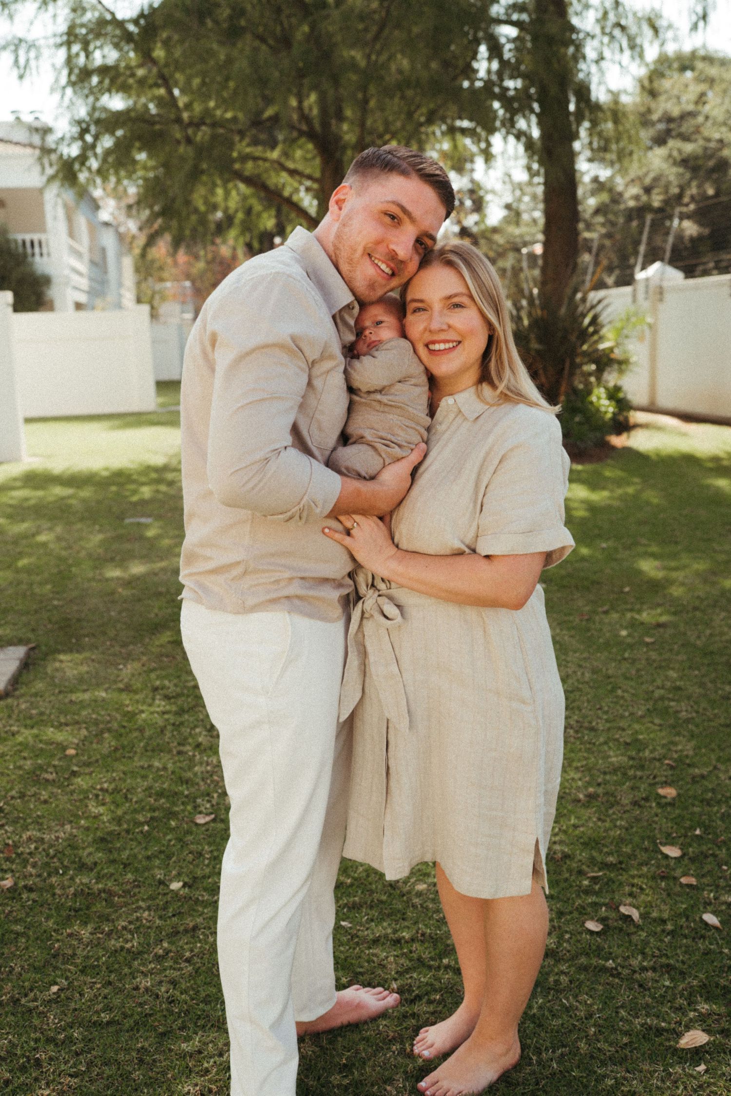 Family photoshoot in a park setting wearing matching neutral colored outfits.