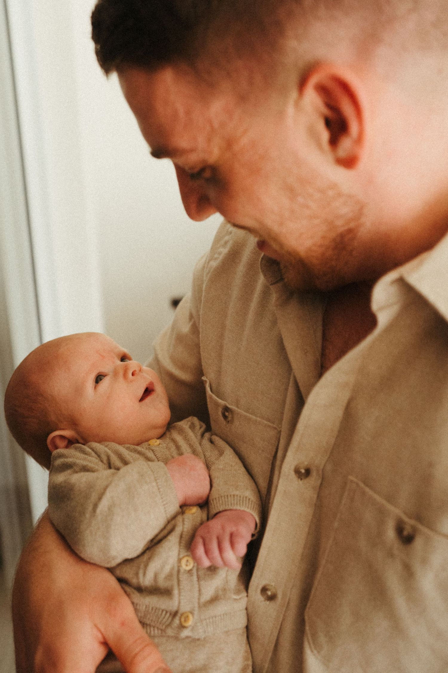 Close-up shots of tender moments between parent and infant in neutral tones.