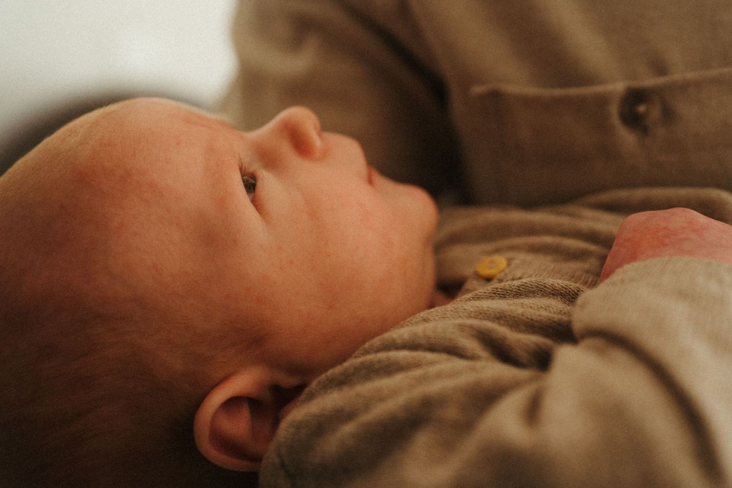 Newborn baby sleeping peacefully in neutral toned clothing.