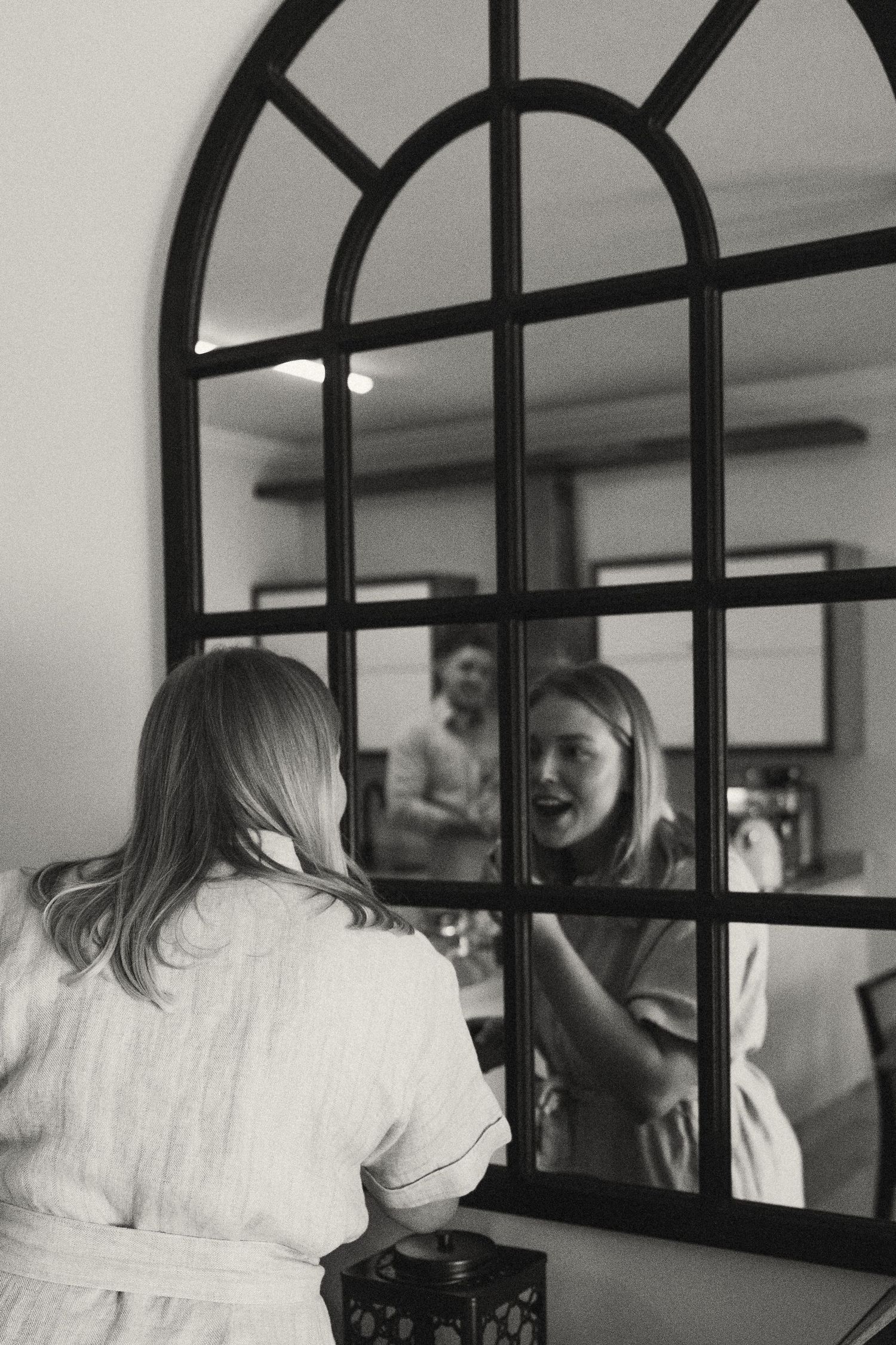 Black metal arched window frames creating geometric reflections in an interior space.