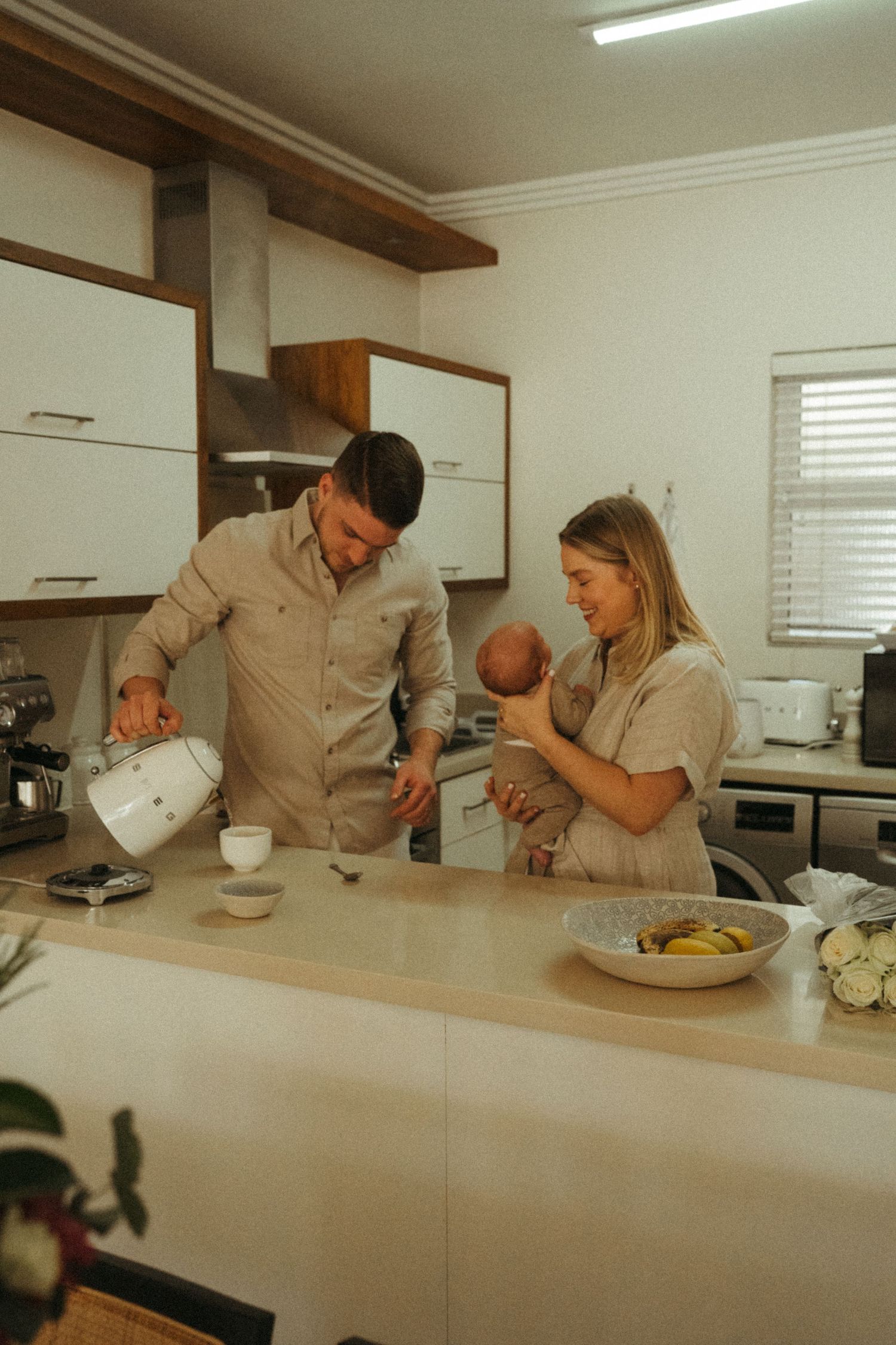 Family gathered in bright modern kitchen sharing casual moment together.