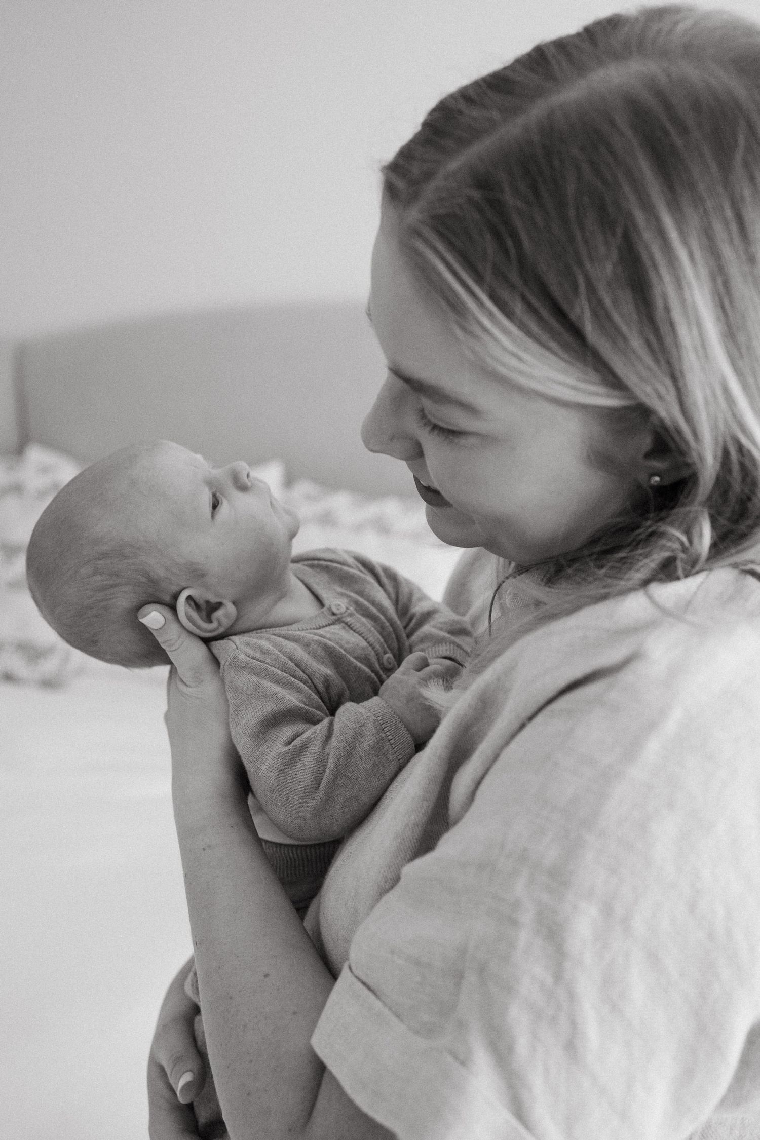 Gentle embrace between parent and infant in soft monochrome lighting.