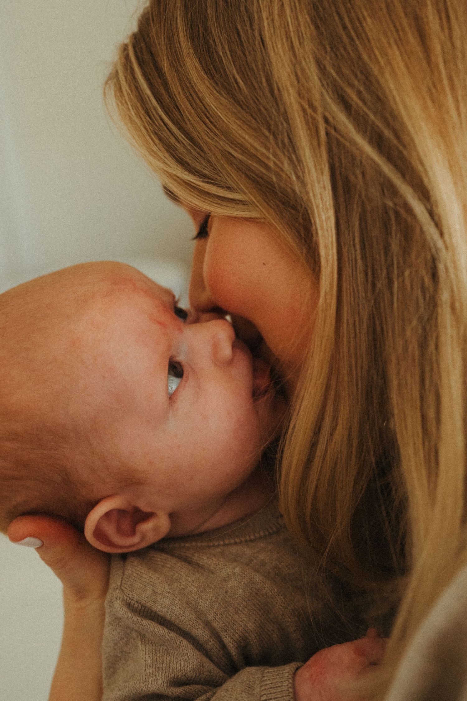 Intimate close-up of parent nuzzling newborn in natural light.