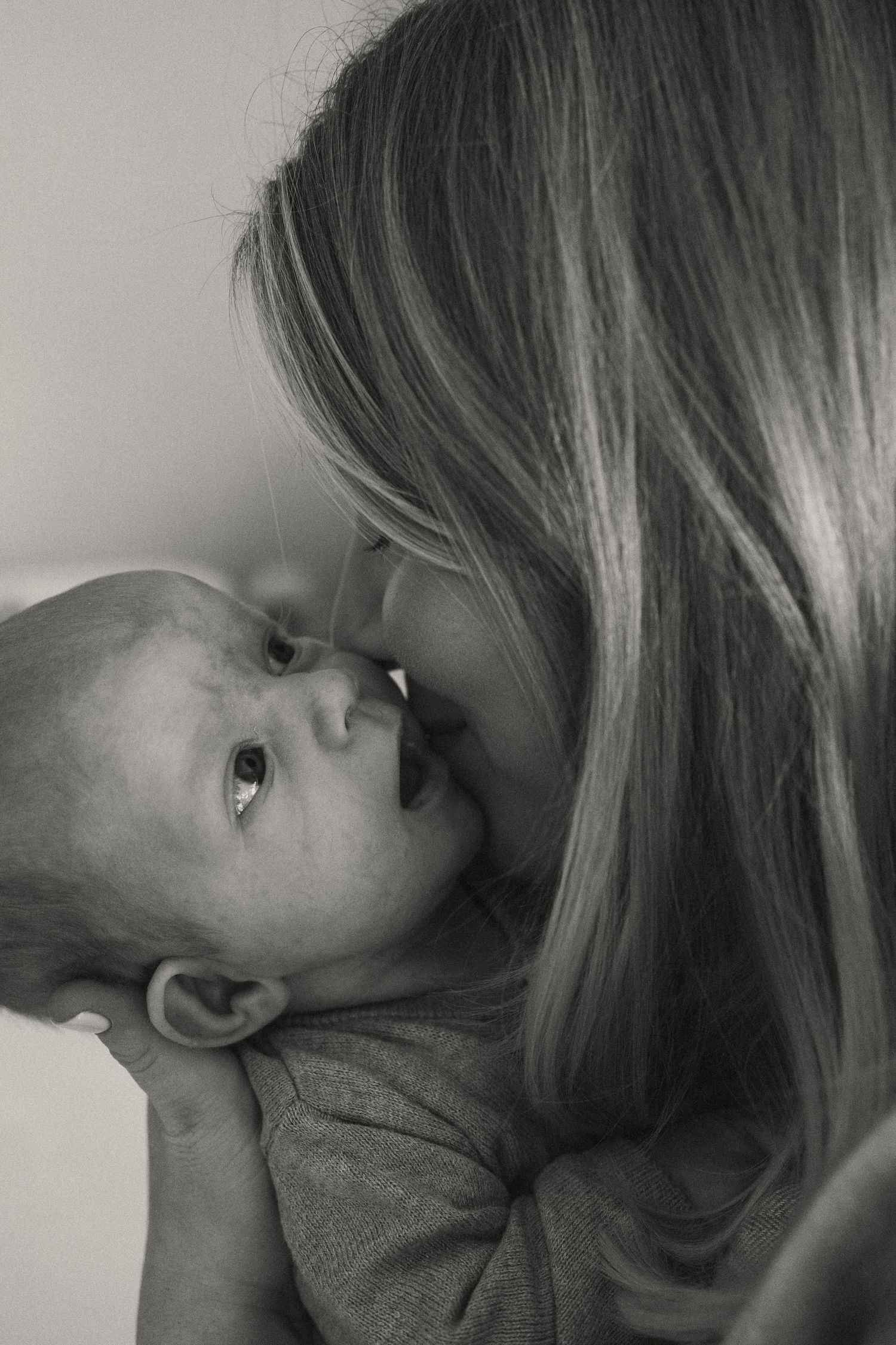 Black and white portrait capturing tender moment between parent and baby.