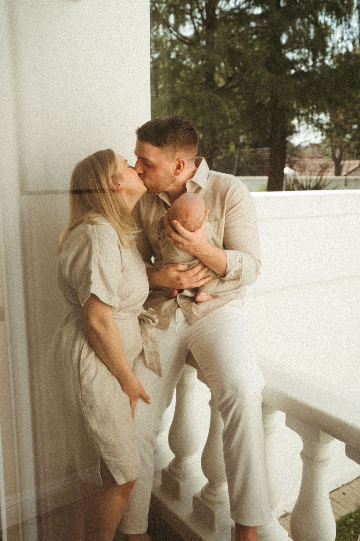 Intimate moments captured between a couple wearing neutral tones on an outdoor terrace.