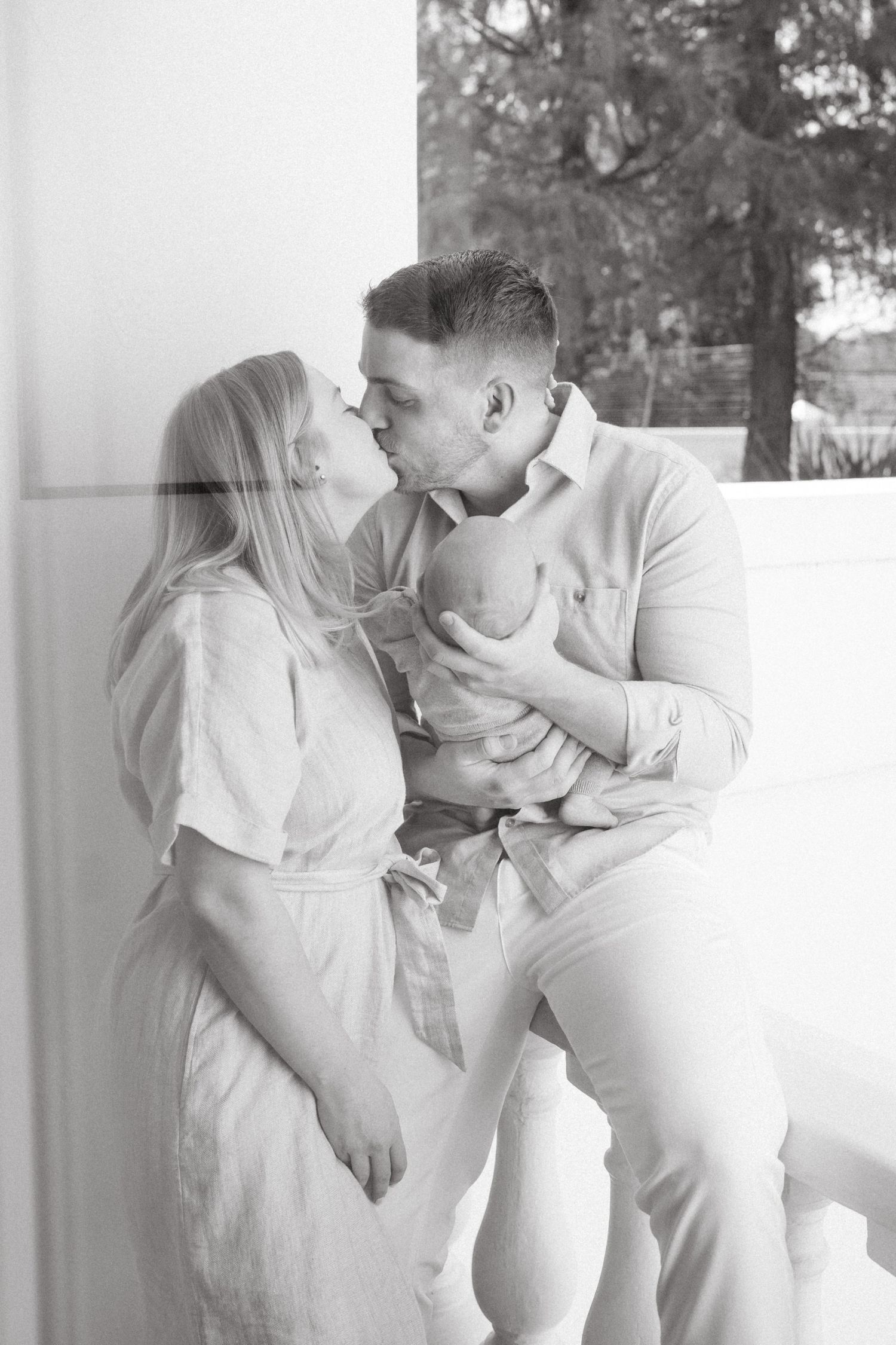 Black and white photo of a couple sharing tender moments along a white balustrade.
