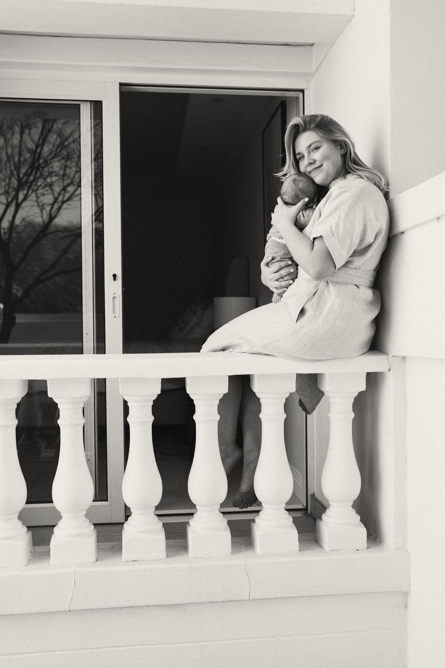 Black and white photos showing tender moments between a couple on a white balcony.