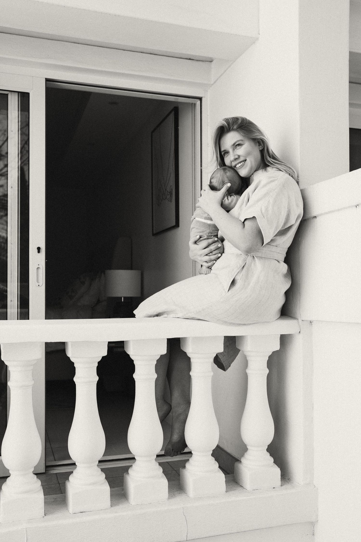 Black and white series capturing intimate moments between a couple on a white balcony.